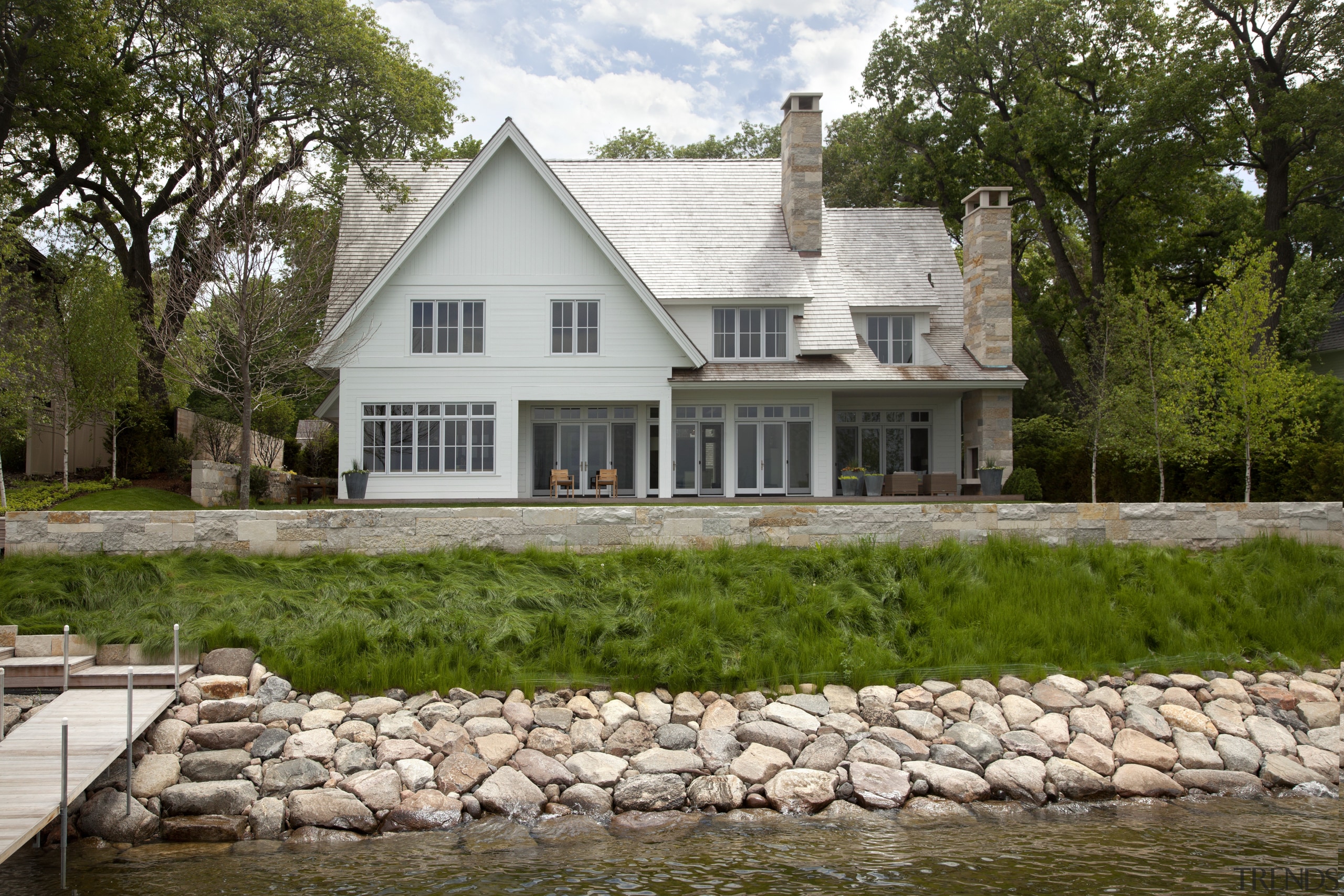 A prime lakefront setting and mature trees enhance cottage, estate, facade, farmhouse, home, house, property, real estate, tree, water, brown, white