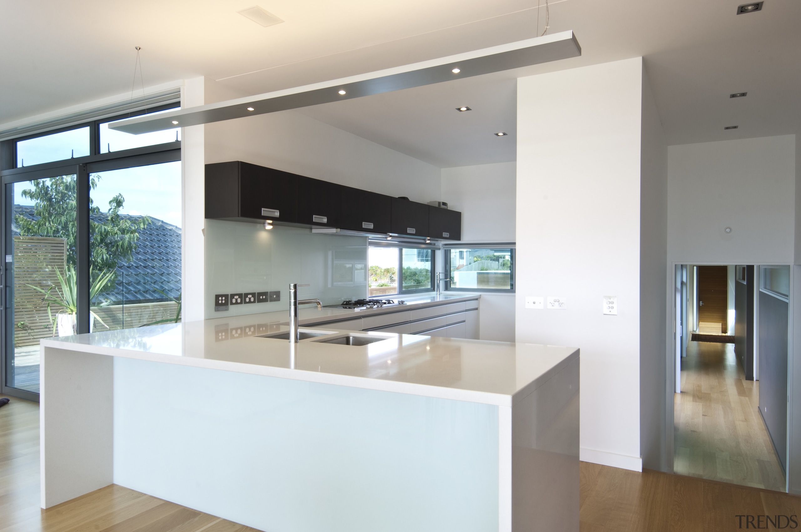 Modern kitchen with wood floors and hallway - architecture, countertop, house, interior design, kitchen, property, real estate, white, gray