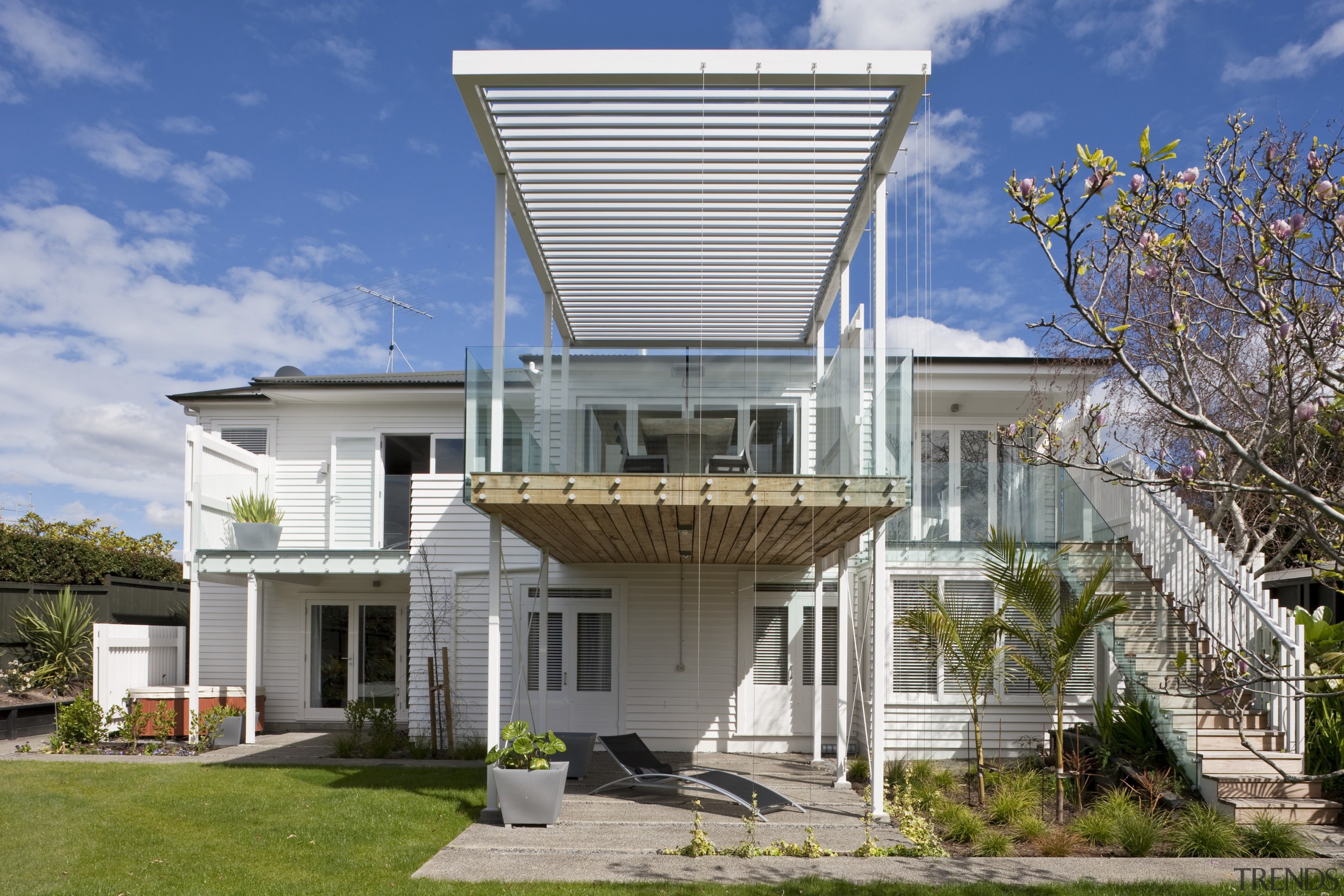 The renovated house features an elevated deck on architecture, building, corporate headquarters, elevation, estate, facade, home, house, mixed use, property, real estate, residential area, roof, villa, gray