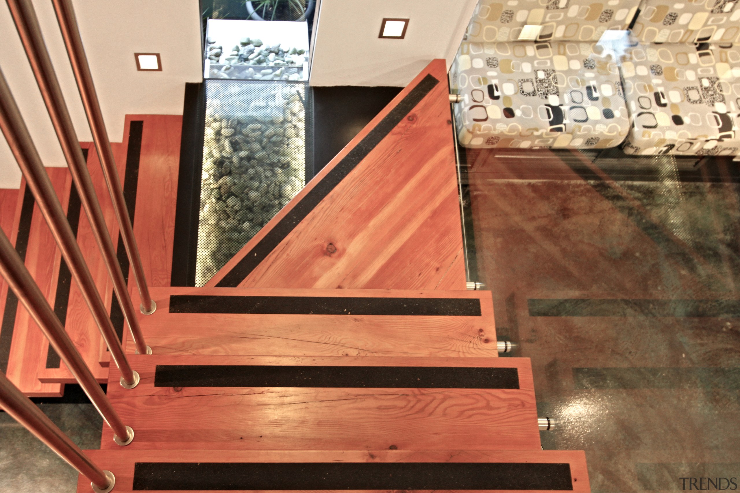 A glass tread on the stairs reveals water floor, flooring, handrail, hardwood, plywood, stairs, wood, wood flooring, wood stain, orange