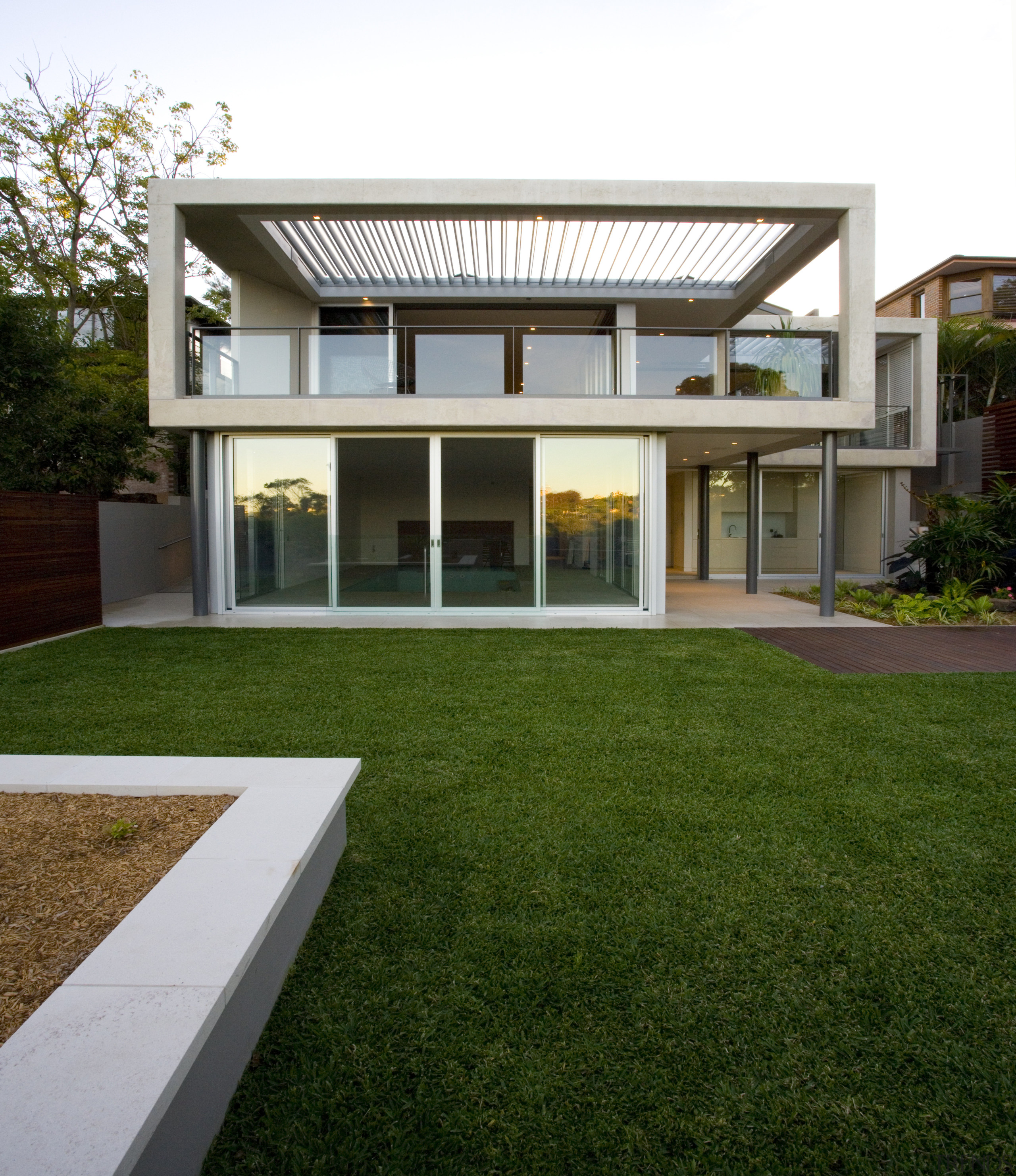 This house offsets its contemporary rectangular side with architecture, backyard, courtyard, elevation, estate, facade, grass, home, house, lawn, property, real estate, residential area, siding, window, yard, brown, white