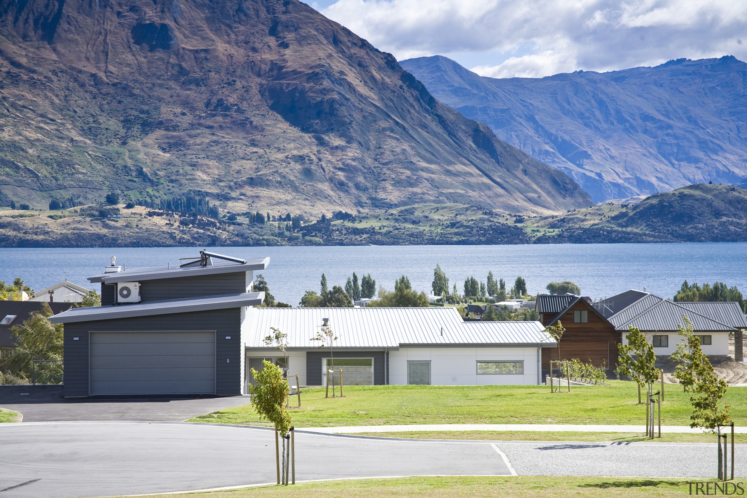 Exterior view of a home which features solar alps, cottage, elevation, estate, fjord, highland, home, house, lake, landscape, mountain, mountain range, property, real estate, residential area, roof, sky, suburb, tree, white