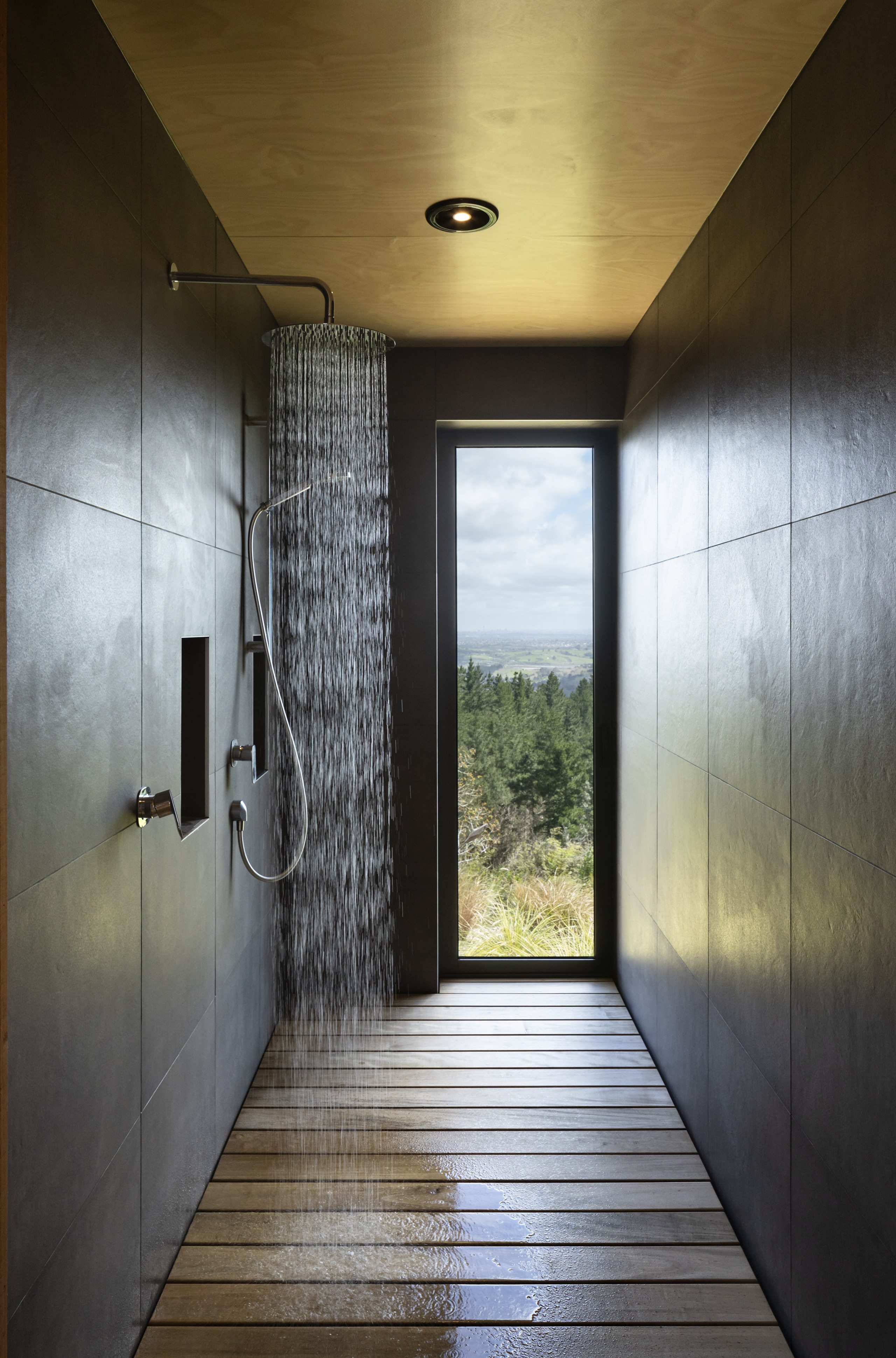 Cocooned in moody, large-scale tiles the shower space 
