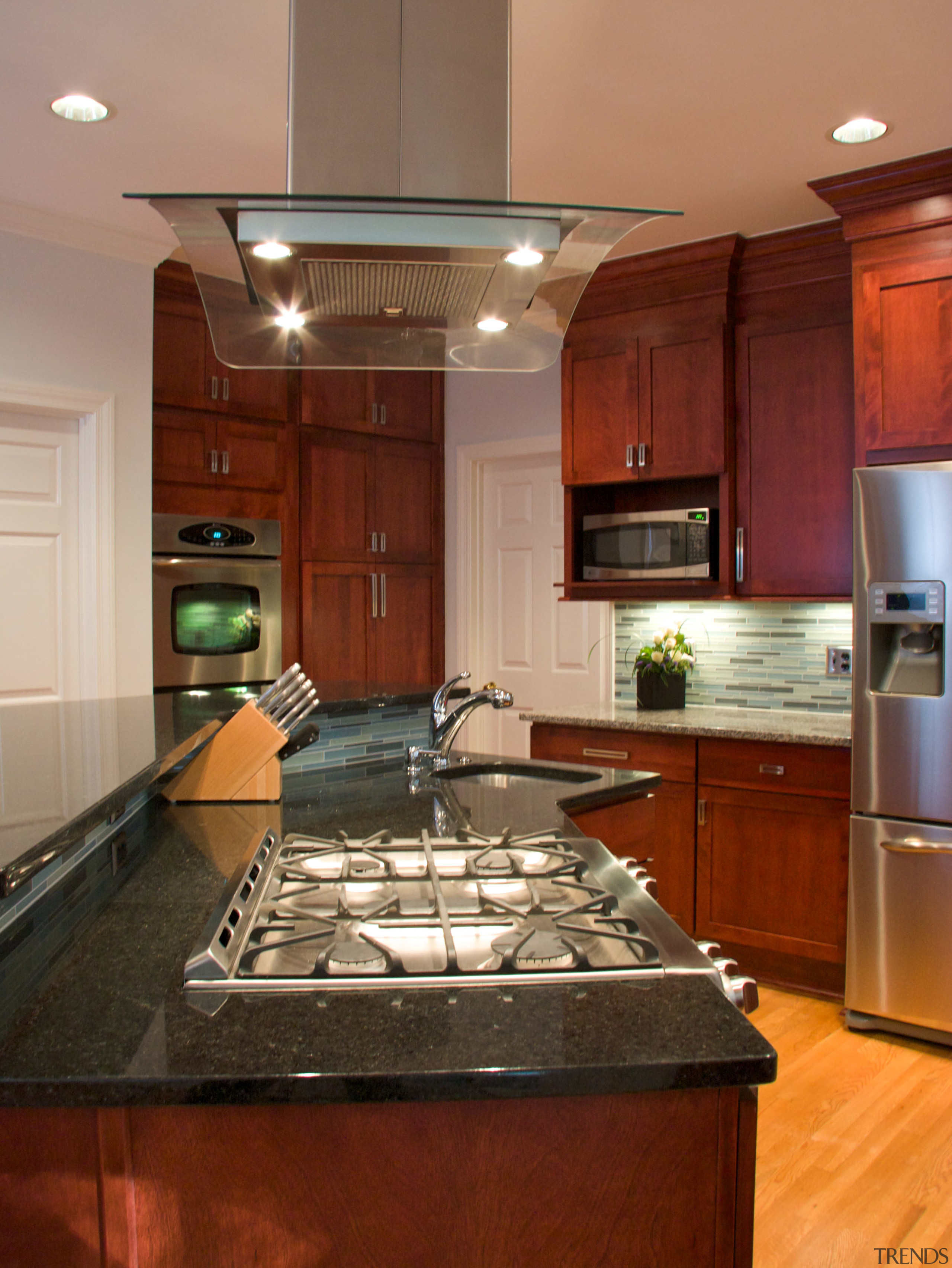 View of a wooden kitchen designed by Instinctive cabinetry, countertop, cuisine classique, flooring, hardwood, interior design, kitchen, room, under cabinet lighting, wood flooring, red, orange