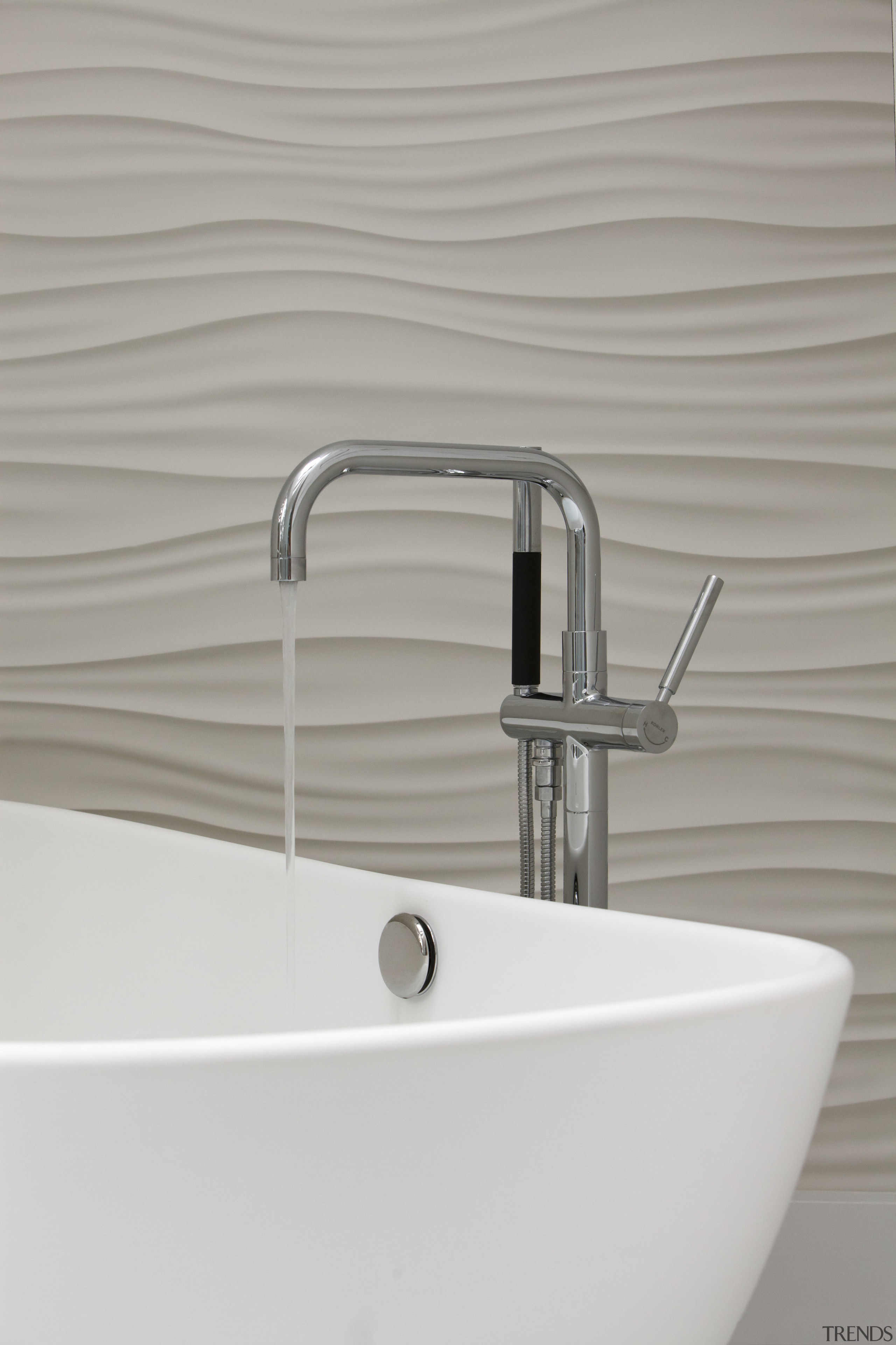 Close-up of a modern, floor-mounted bathtub filler, with bathroom sink, plumbing fixture, product design, sink, tap, gray