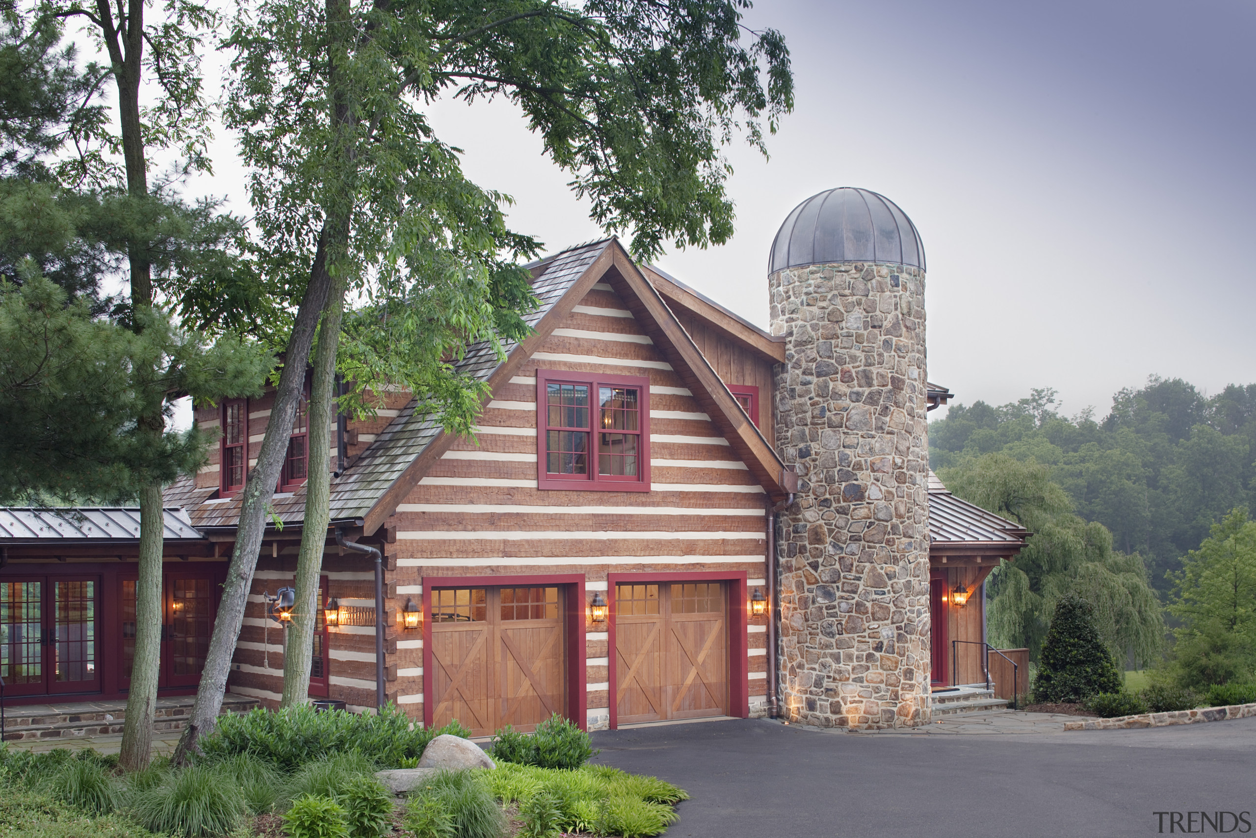 View of wooden building with two garages. - cottage, estate, facade, home, house, log cabin, property, real estate, residential area, roof, tree, gray