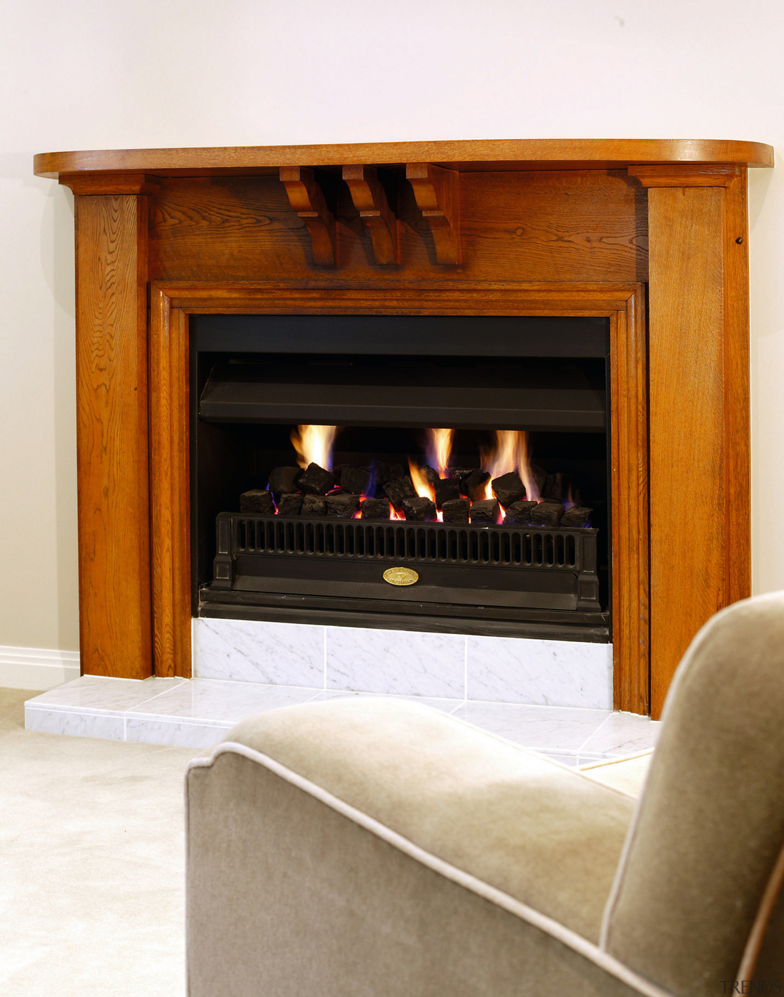 A fireplace with a wooden surround.  There fireplace, furniture, hearth, heat, wood burning stove, white, brown