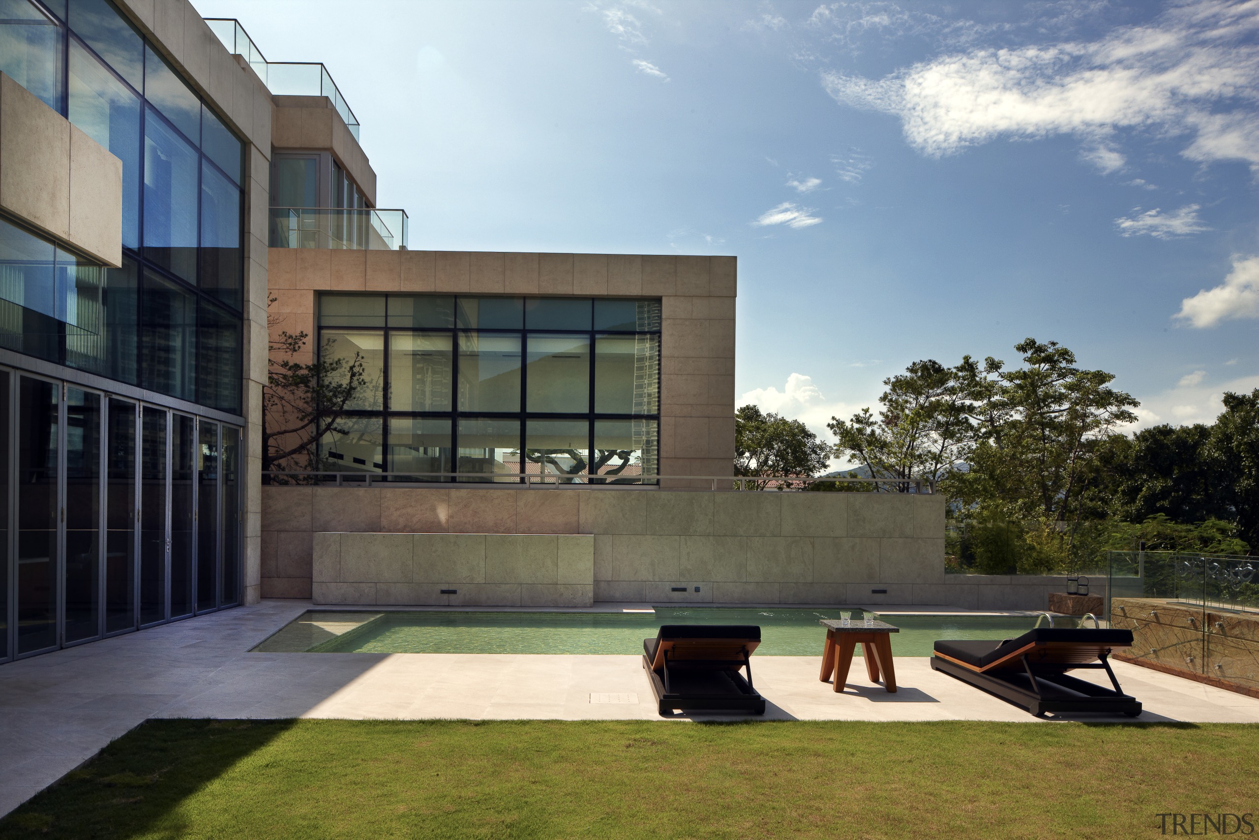 View of pool area at a contemporary home. apartment, architecture, building, condominium, corporate headquarters, daytime, estate, facade, grass, home, house, real estate, residential area, sky, window, brown