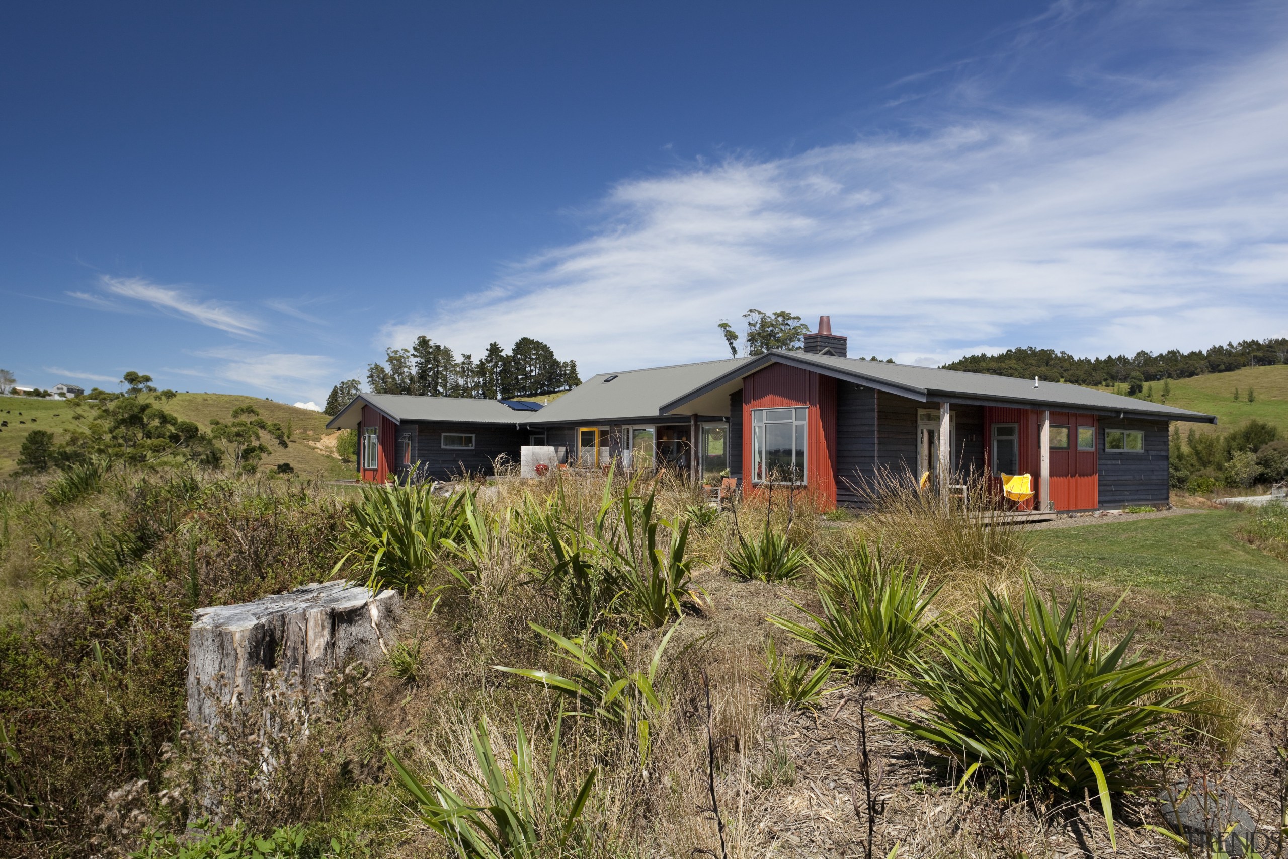 View of exterior with red and black walls cloud, cottage, home, house, land lot, landscape, mountain, plant community, property, real estate, rural area, sky, brown