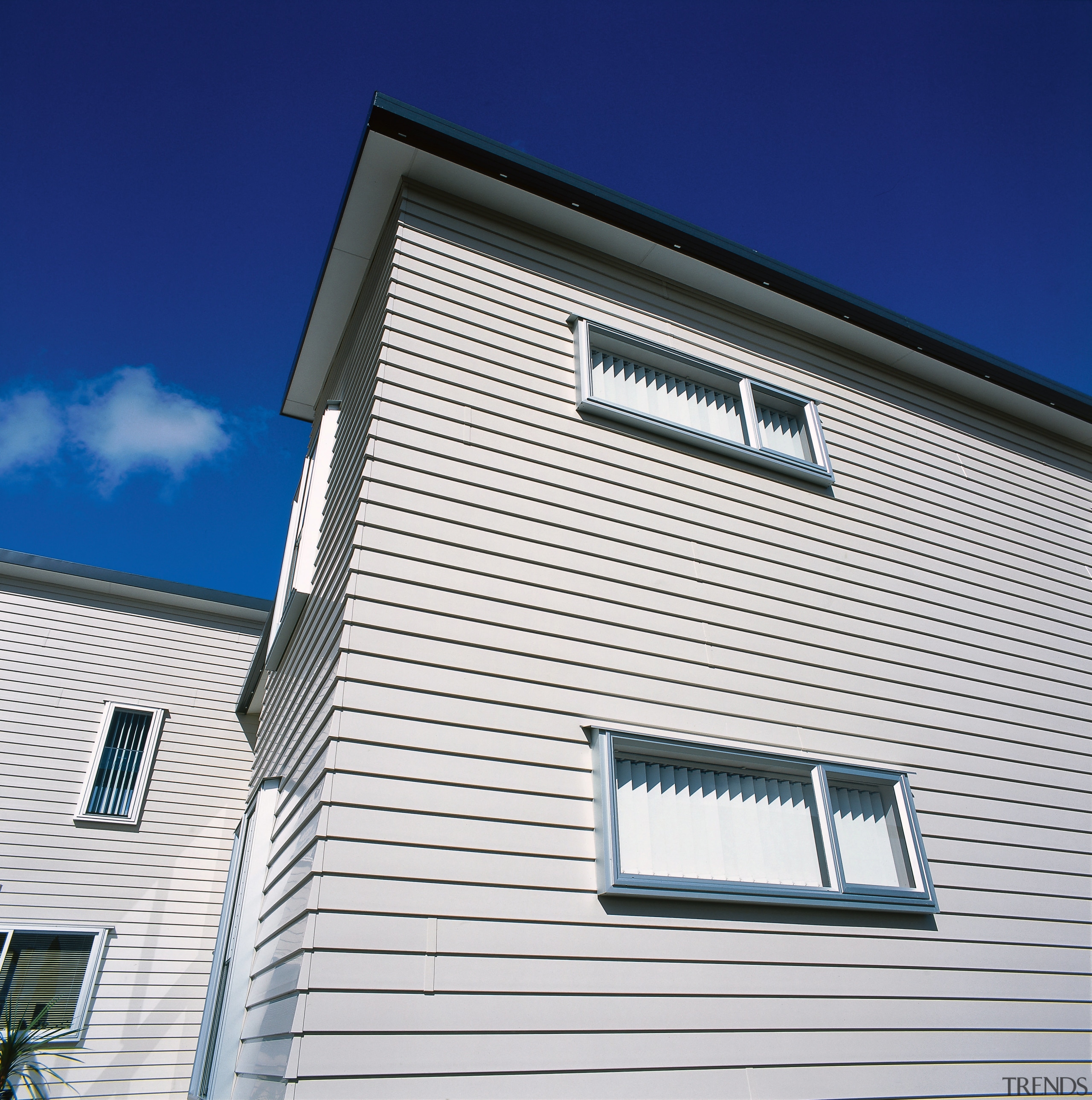 Exterior of two-storey home with cream weatherboard cladding. architecture, building, commercial building, daylighting, daytime, facade, home, house, line, real estate, residential area, roof, siding, sky, window, white, blue