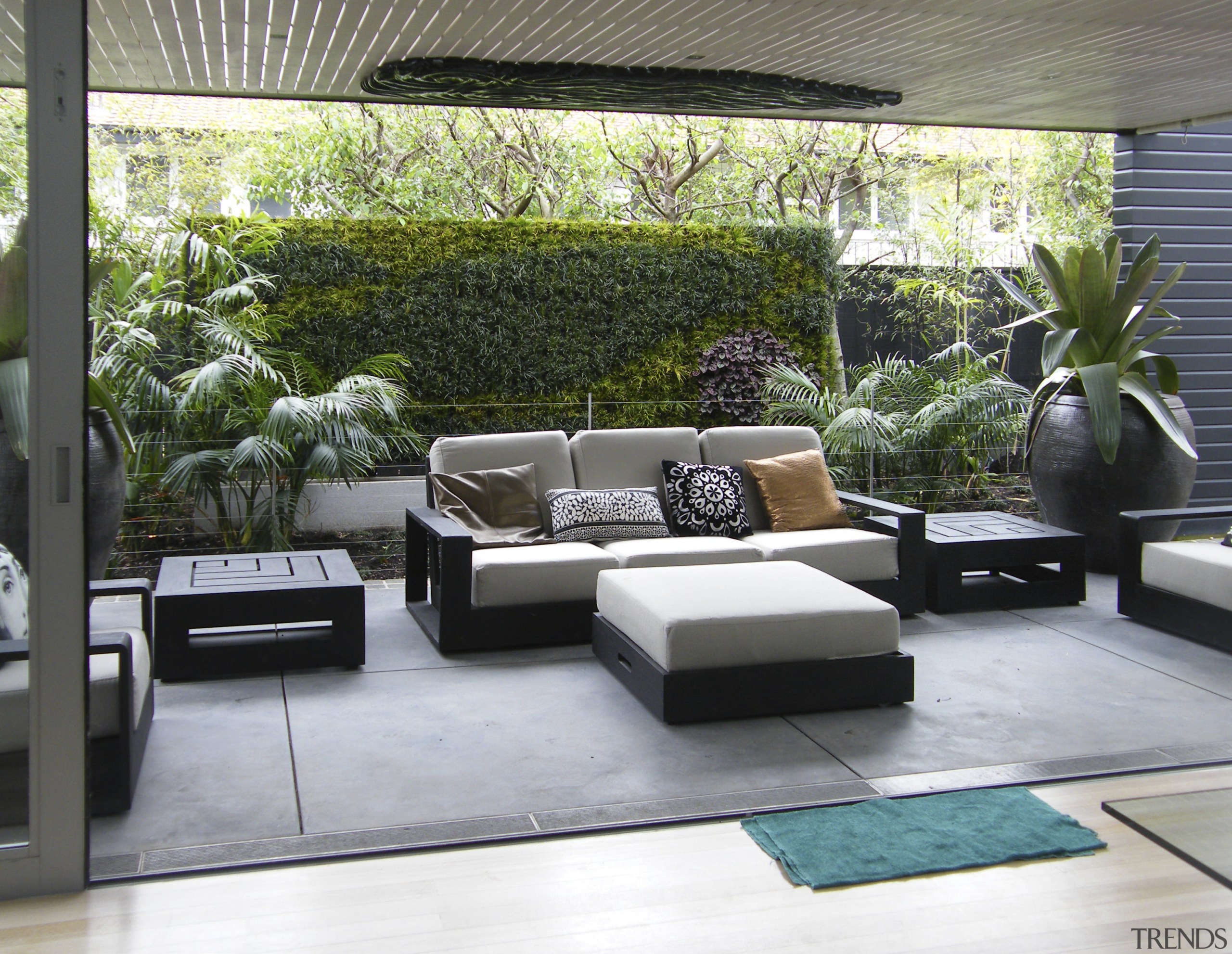 View of outdoor living space filled with mature floor, furniture, house, interior design, living room, outdoor structure, patio, property, real estate, gray