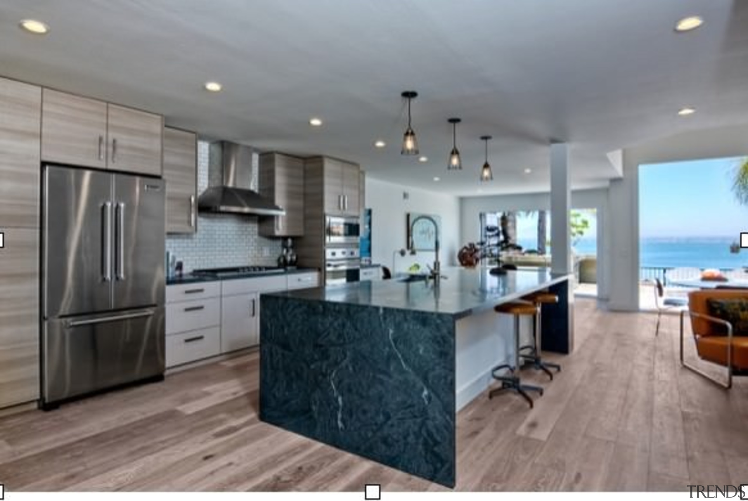 A waterfall island provides space for food prep cabinetry, countertop, cuisine classique, floor, flooring, hardwood, interior design, kitchen, real estate, room, wood flooring, gray