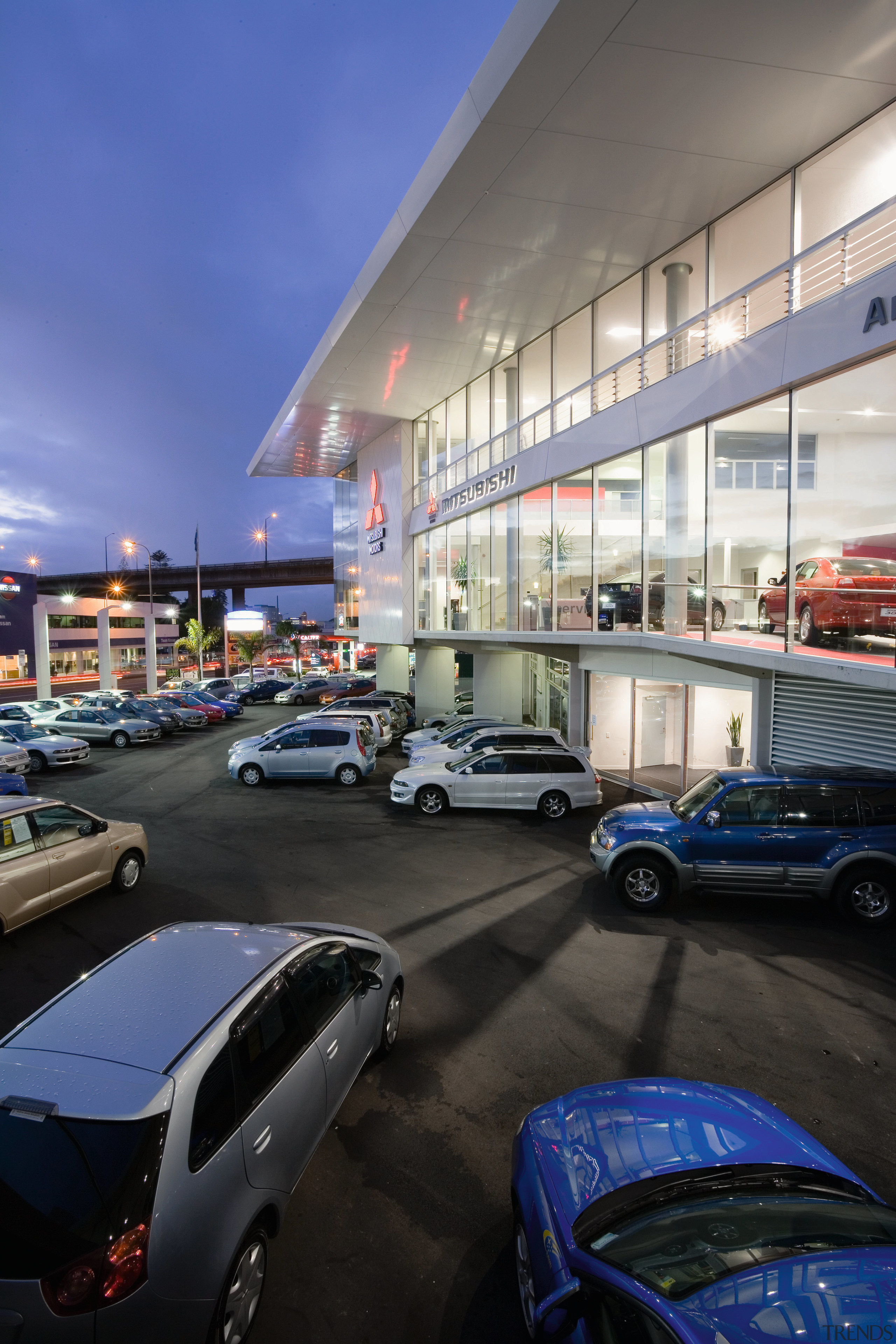 A view of the Mitsubishi Motors building. - architecture, automotive design, building, car, car dealership, city, executive car, family car, land vehicle, luxury vehicle, metropolitan area, mid size car, motor vehicle, parking lot, residential area, sky, sport utility vehicle, vehicle, black, blue