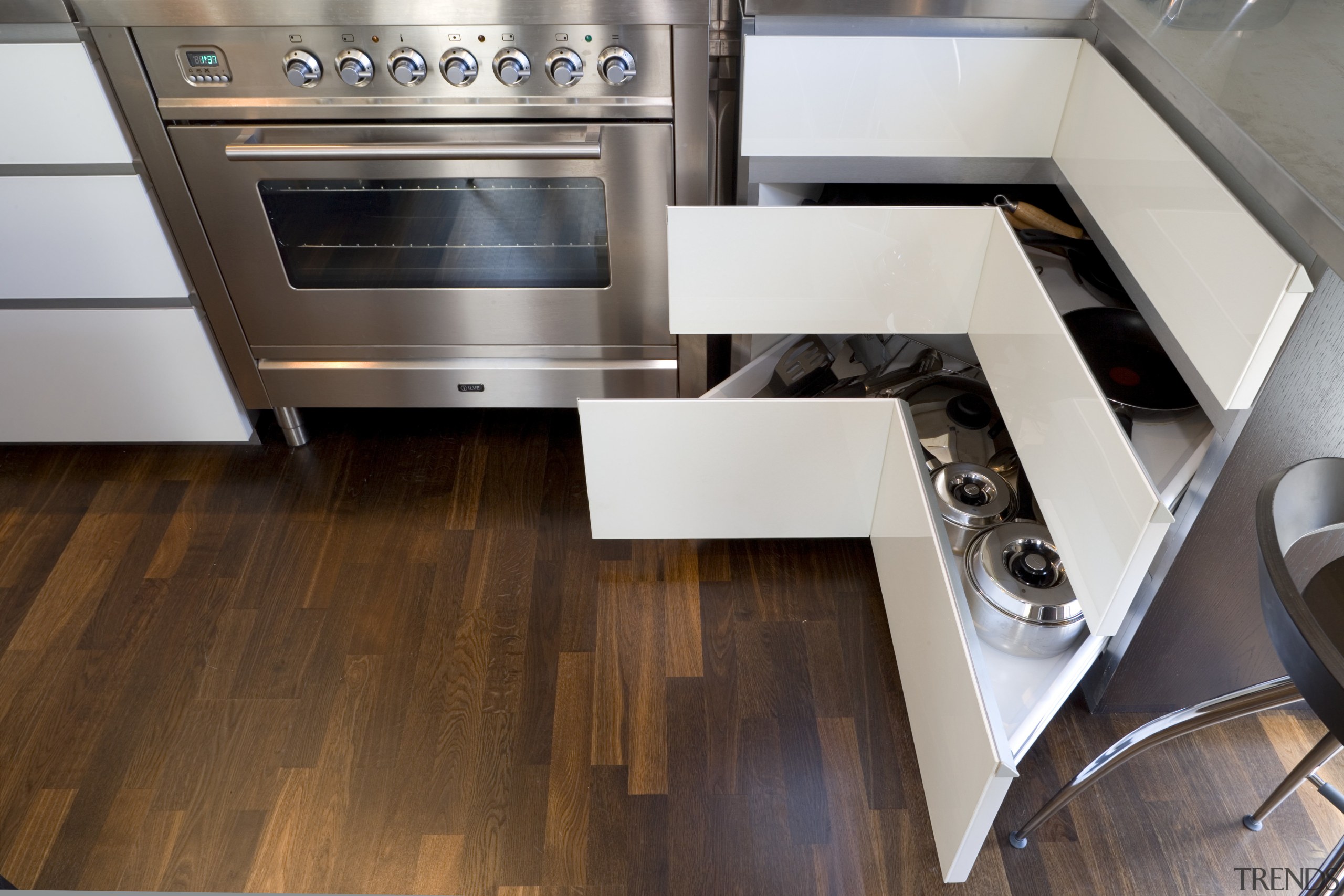 View of kitchen and living area designed by countertop, floor, flooring, hardwood, home appliance, kitchen, kitchen stove, wood, wood flooring, gray, brown