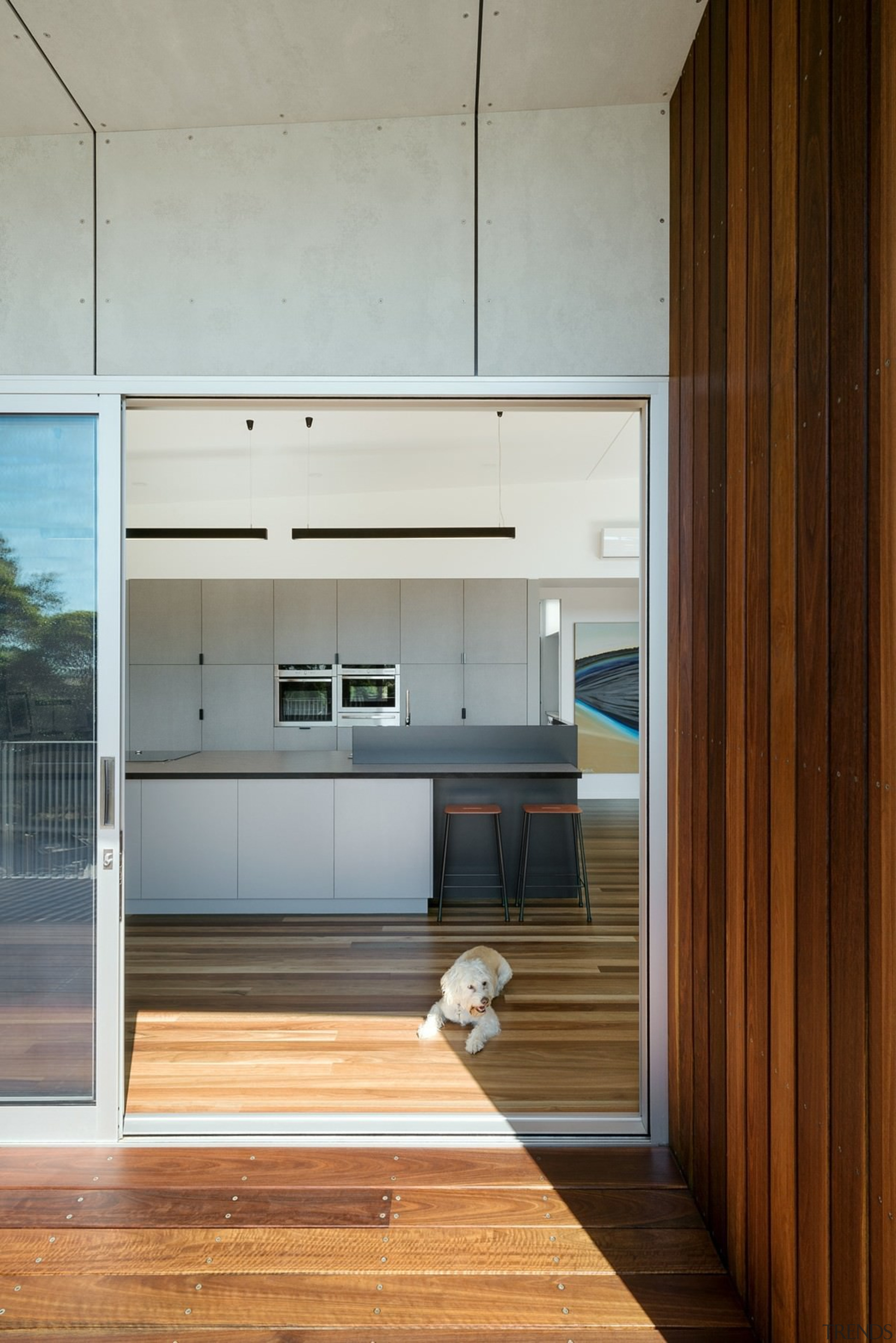 The wood from the deck runs up into architecture, cabinetry, countertop, floor, hardwood, house, interior design, kitchen, wood flooring, gray, brown