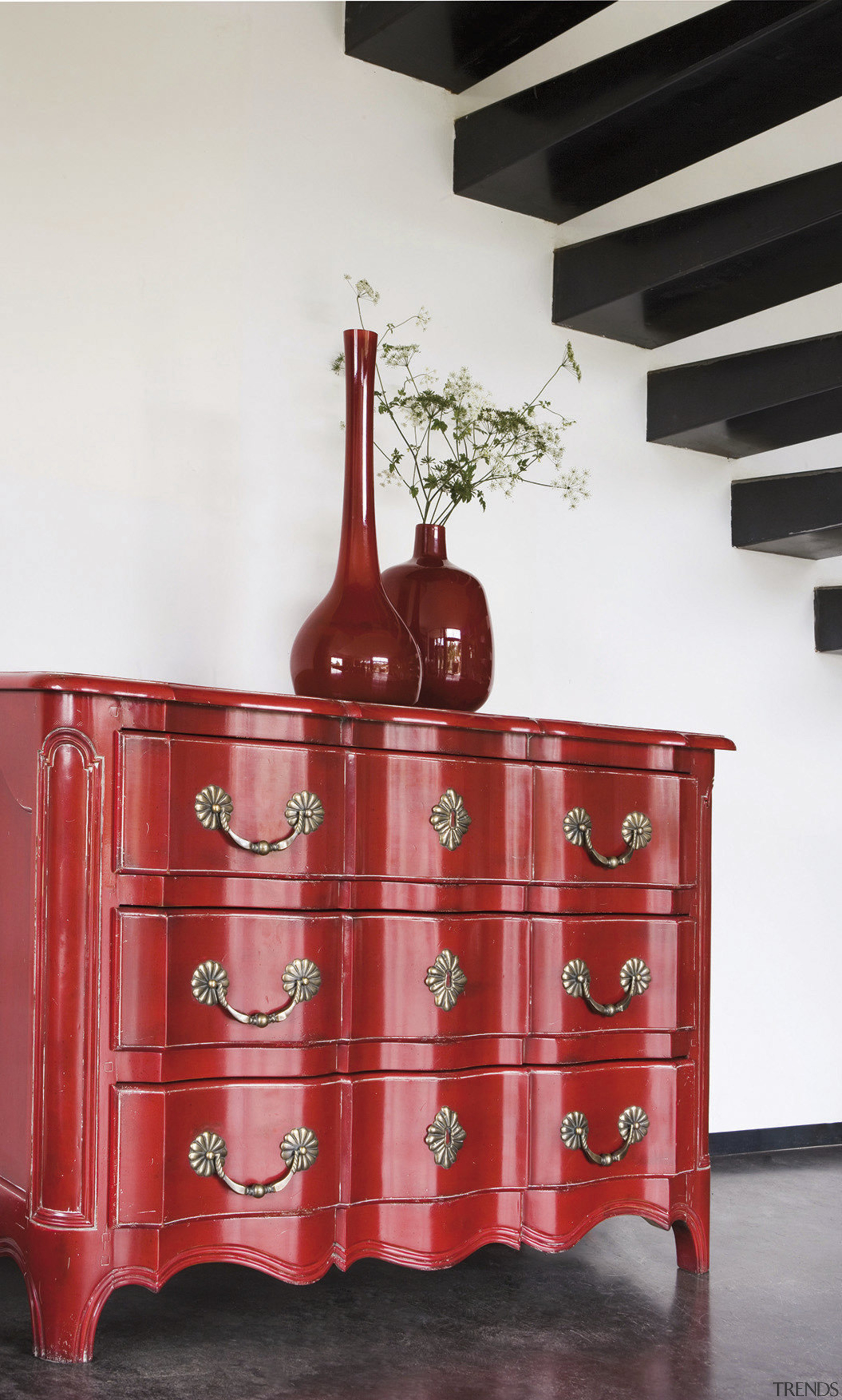 Red striped drawers with red vases under stairway. chest of drawers, drawer, furniture, table, white, red