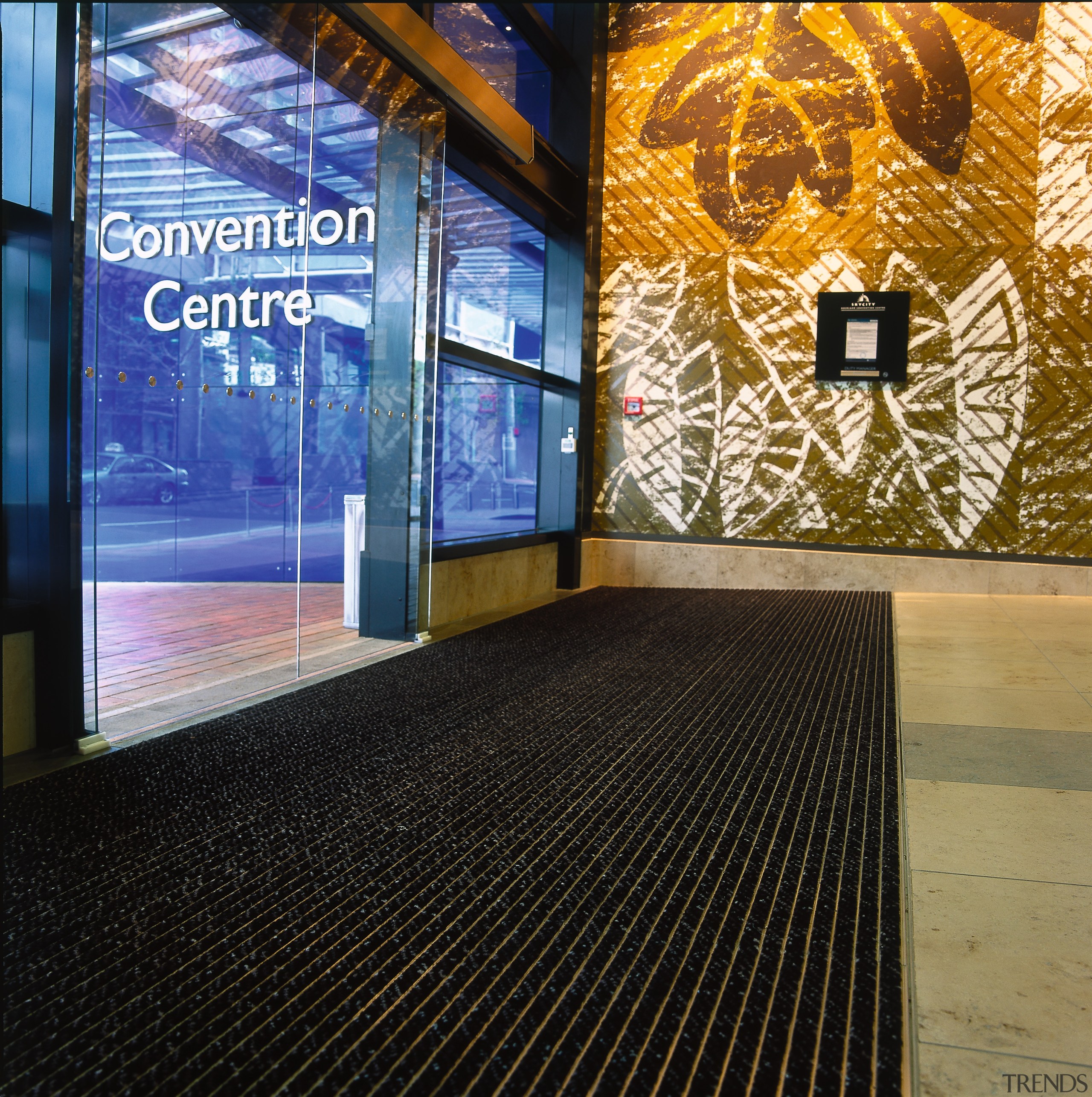 Entranceway of convention through glass doors with striped flooring, black