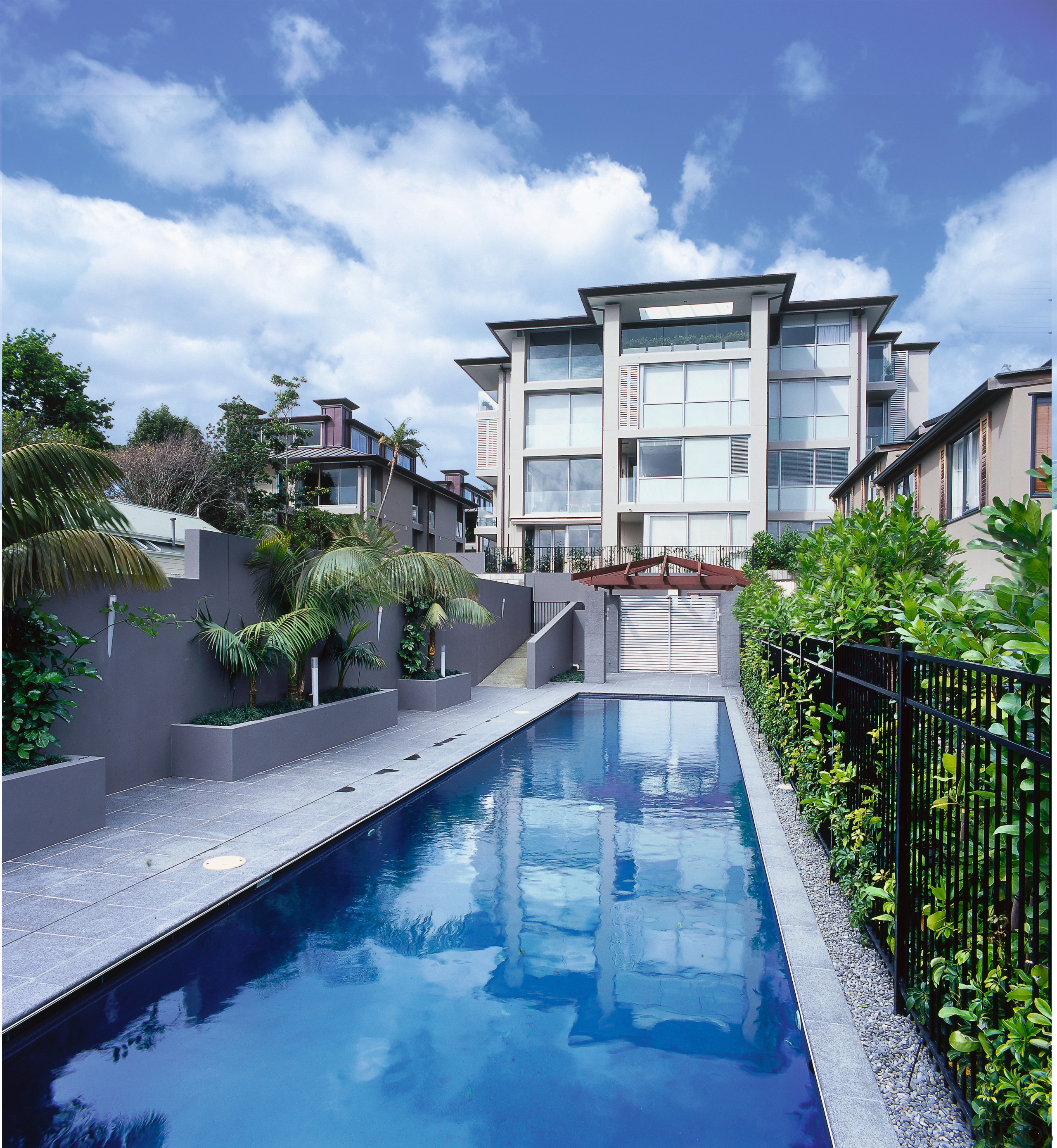 An exterior view of the apartment, the gardens architecture, condominium, estate, home, house, property, real estate, residential area, resort, sky, swimming pool, villa, water, blue, white