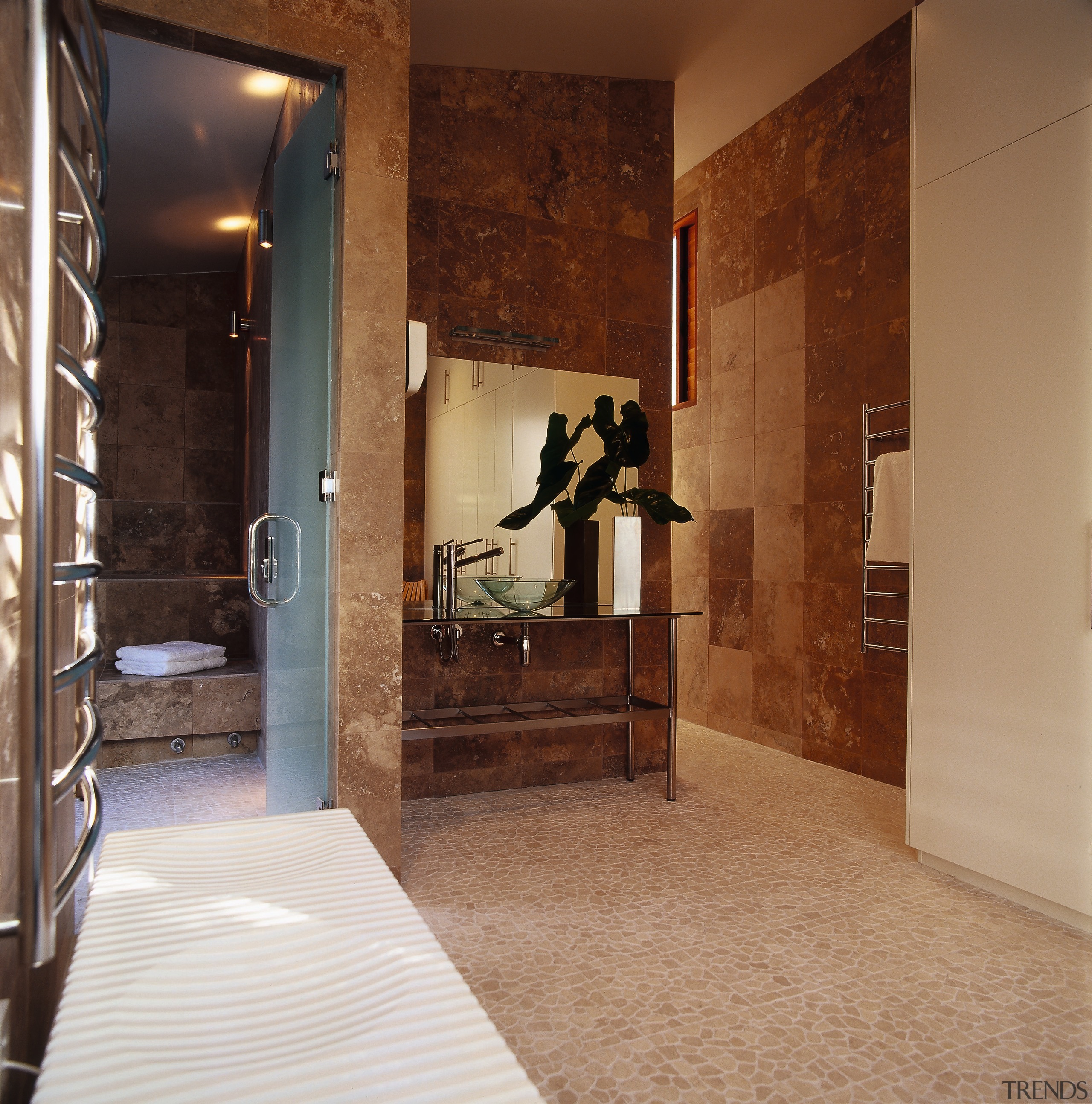 A luxurious bathroom featuring a steam room, vanity bathroom, floor, flooring, interior design, lobby, room, tile, wall, brown