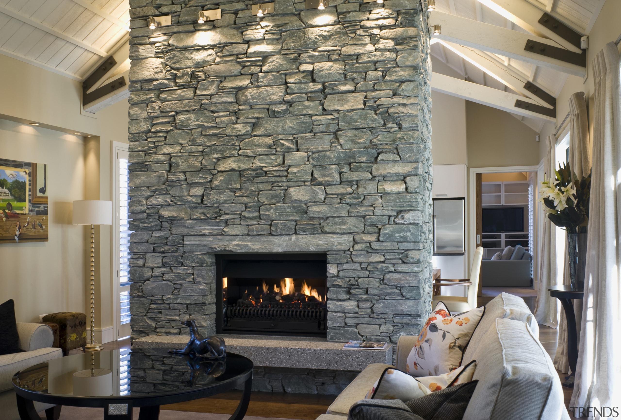 The central schist fireplace is left unadorned, as ceiling, fireplace, hearth, home, interior design, living room, wall, gray