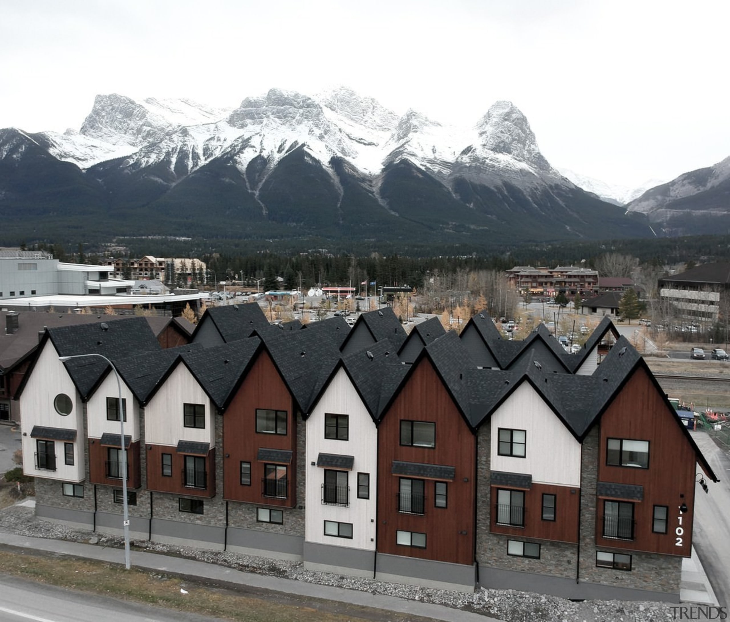 The buildings add to the character of the alps, building, city, home, house, mountain, mountain range, neighbourhood, real estate, residential area, roof, sky, snow, suburb, town, winter, white, black, gray