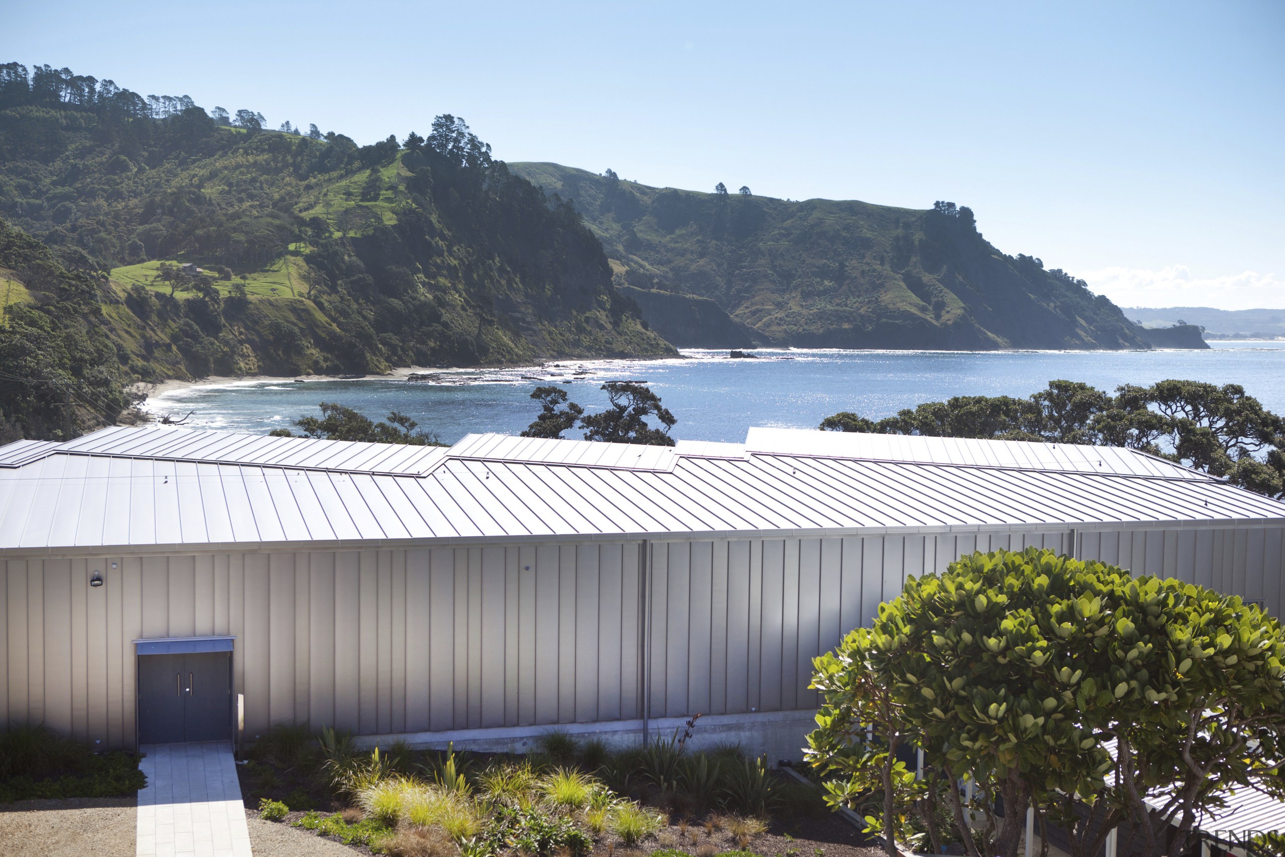 View over building to sea. - View over architecture, house, outdoor structure, real estate, roof, sky, tree, water, white