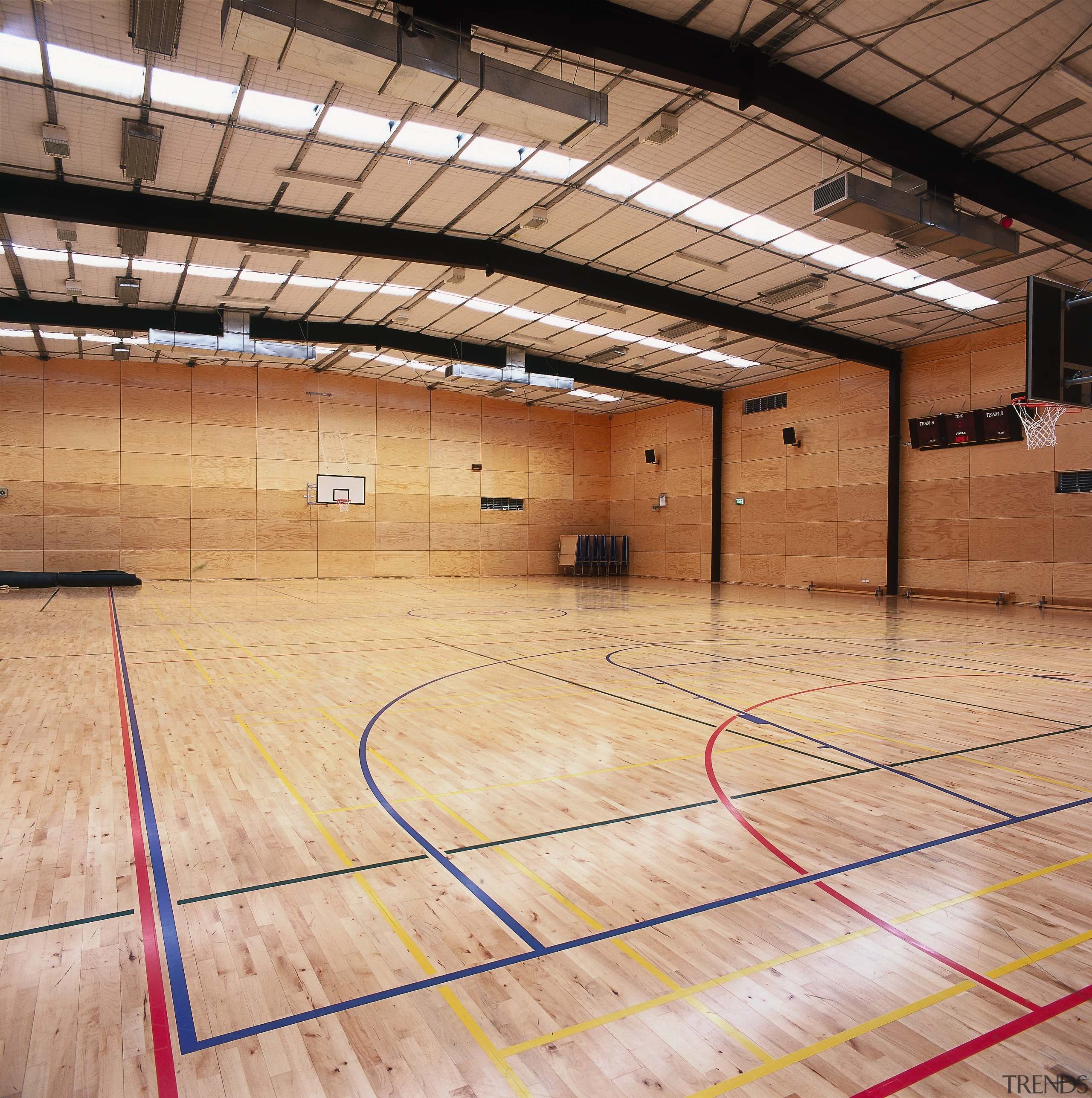 View of large school gym with timber flooring. basketball court, ceiling, floor, flooring, hardwood, indoor games and sports, leisure centre, net, sport venue, sports, structure, wood, wood flooring, orange