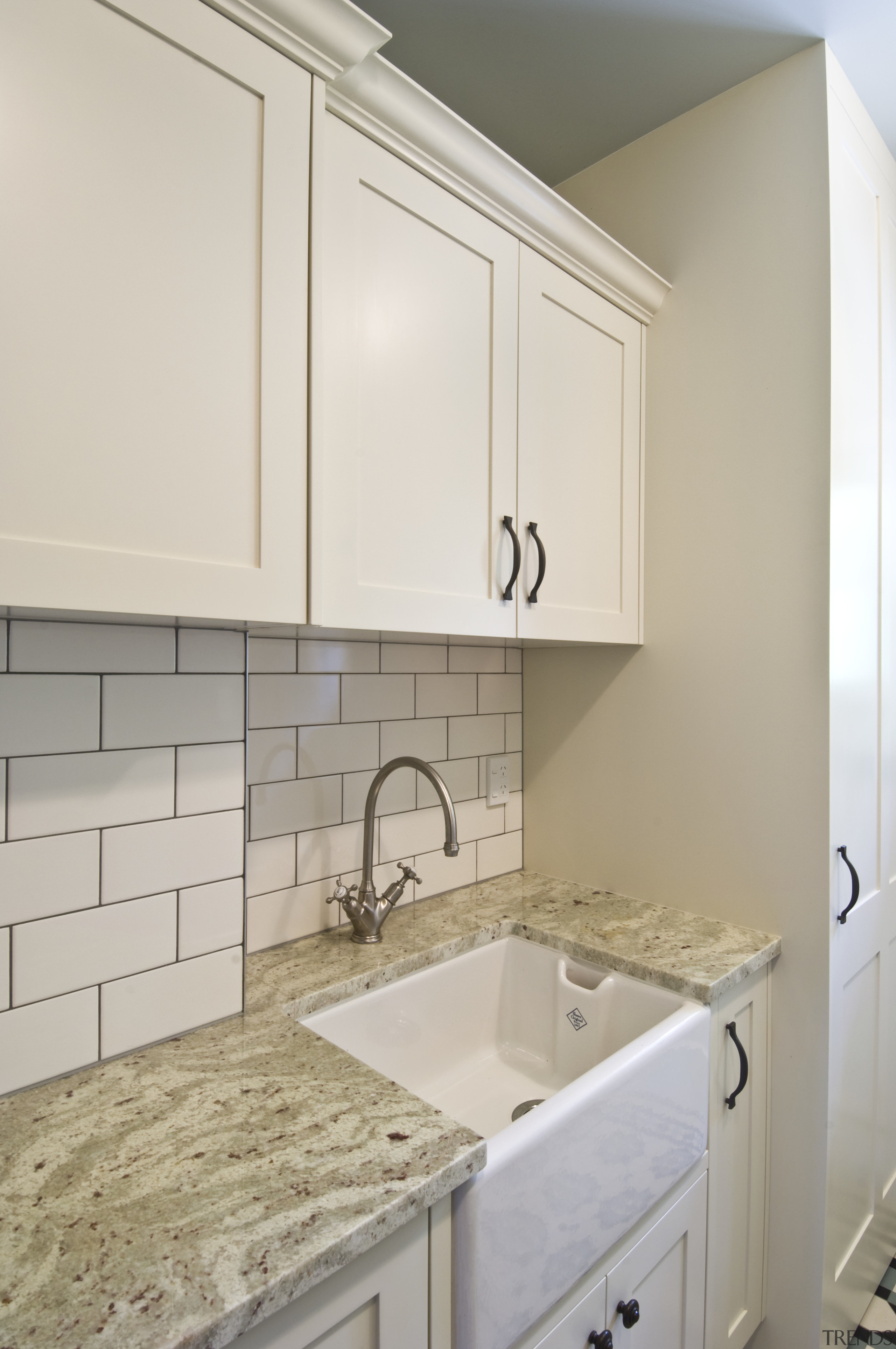 View of laundry, featuring a white butler's sink, bathroom, bathroom accessory, bathroom cabinet, cabinetry, countertop, floor, flooring, home, interior design, kitchen, laundry room, room, sink, tile, gray