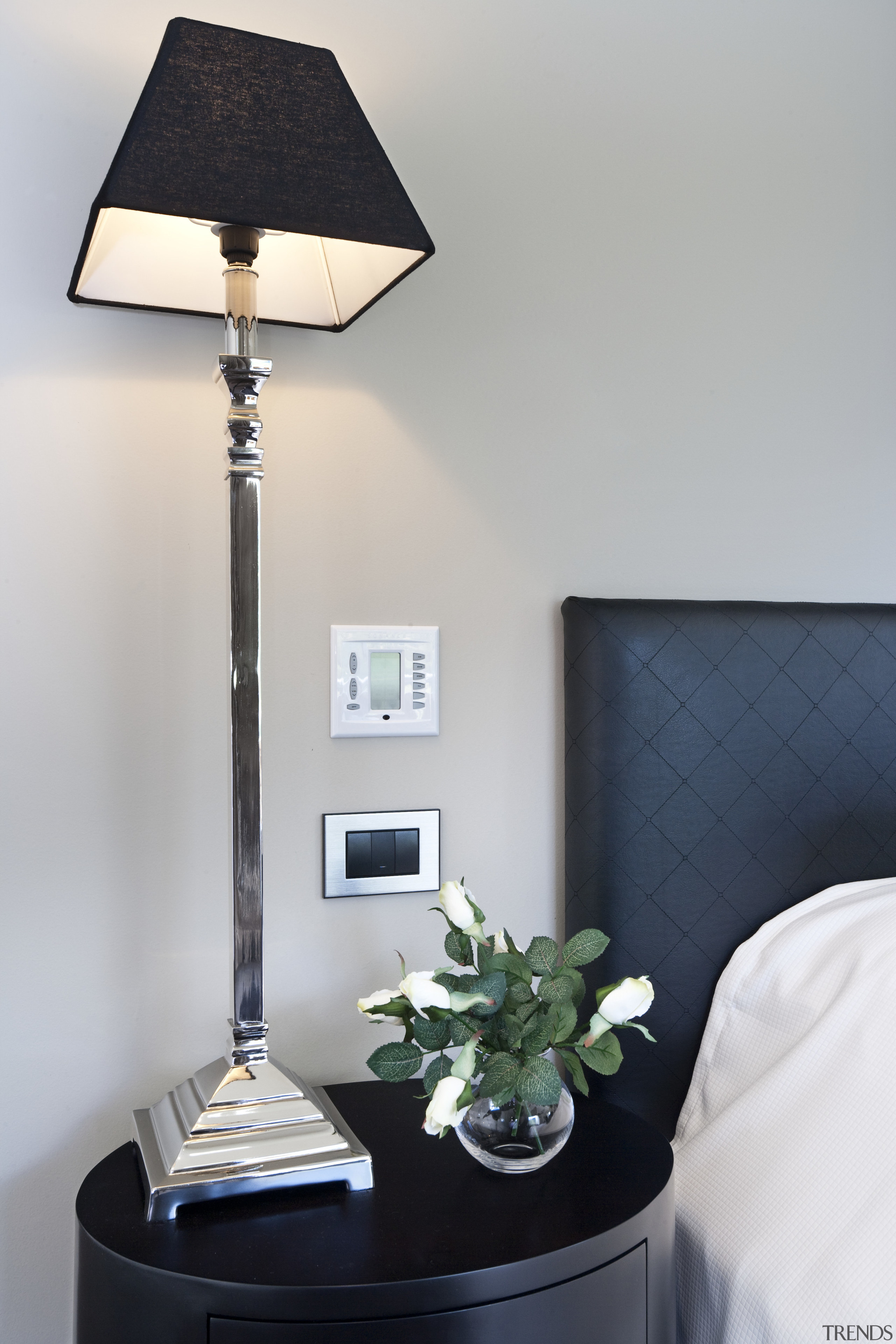 View of bedroom featuring bed with white linen, interior design, lamp, lampshade, light fixture, lighting, lighting accessory, product design, table, gray