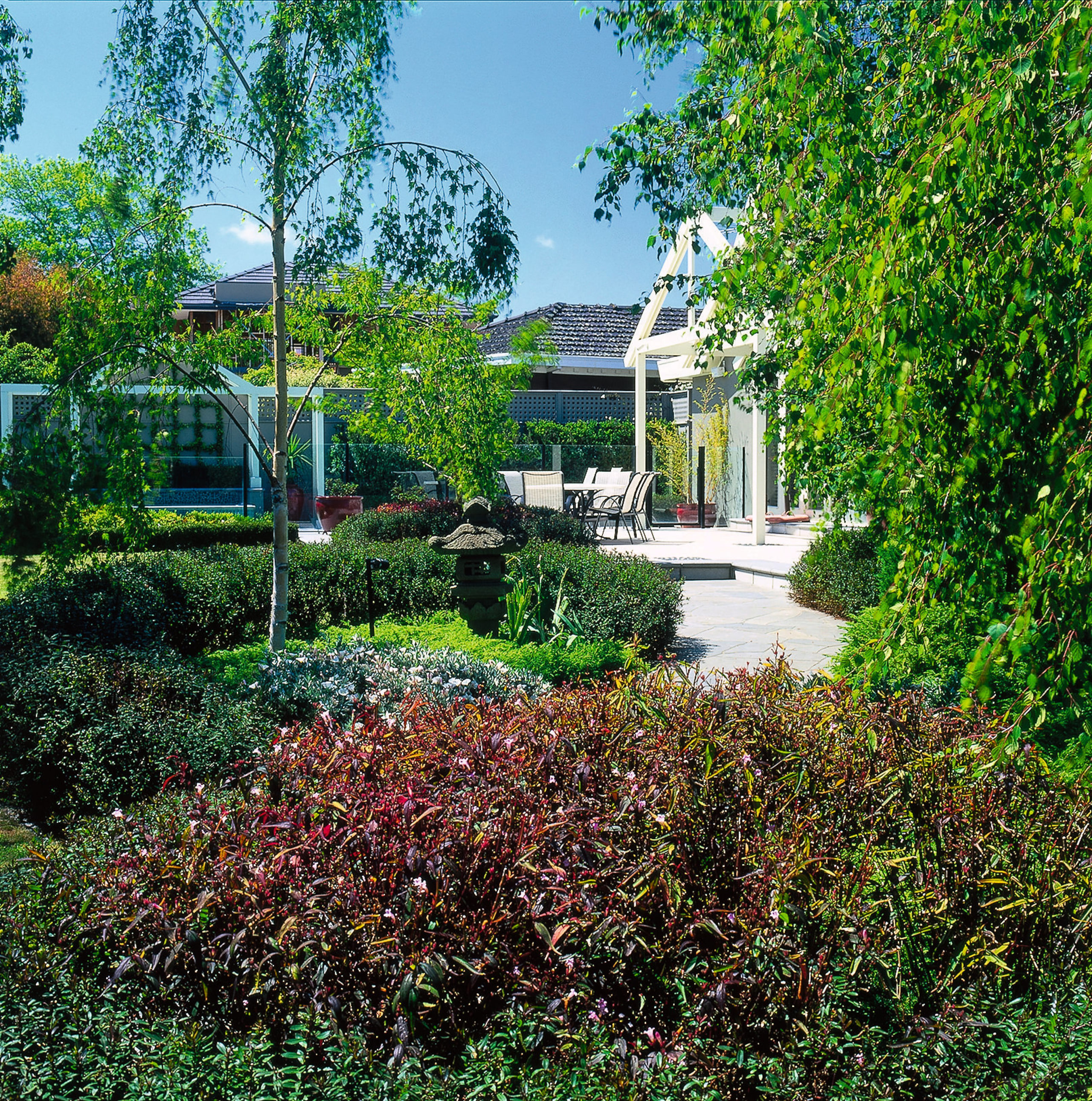 Landscape renovation. Leafy foliage line the slate path botanical garden, cottage, estate, garden, grass, home, house, landscape, landscaping, lawn, leaf, plant, property, real estate, residential area, shrub, tree, vegetation, walkway, yard, green