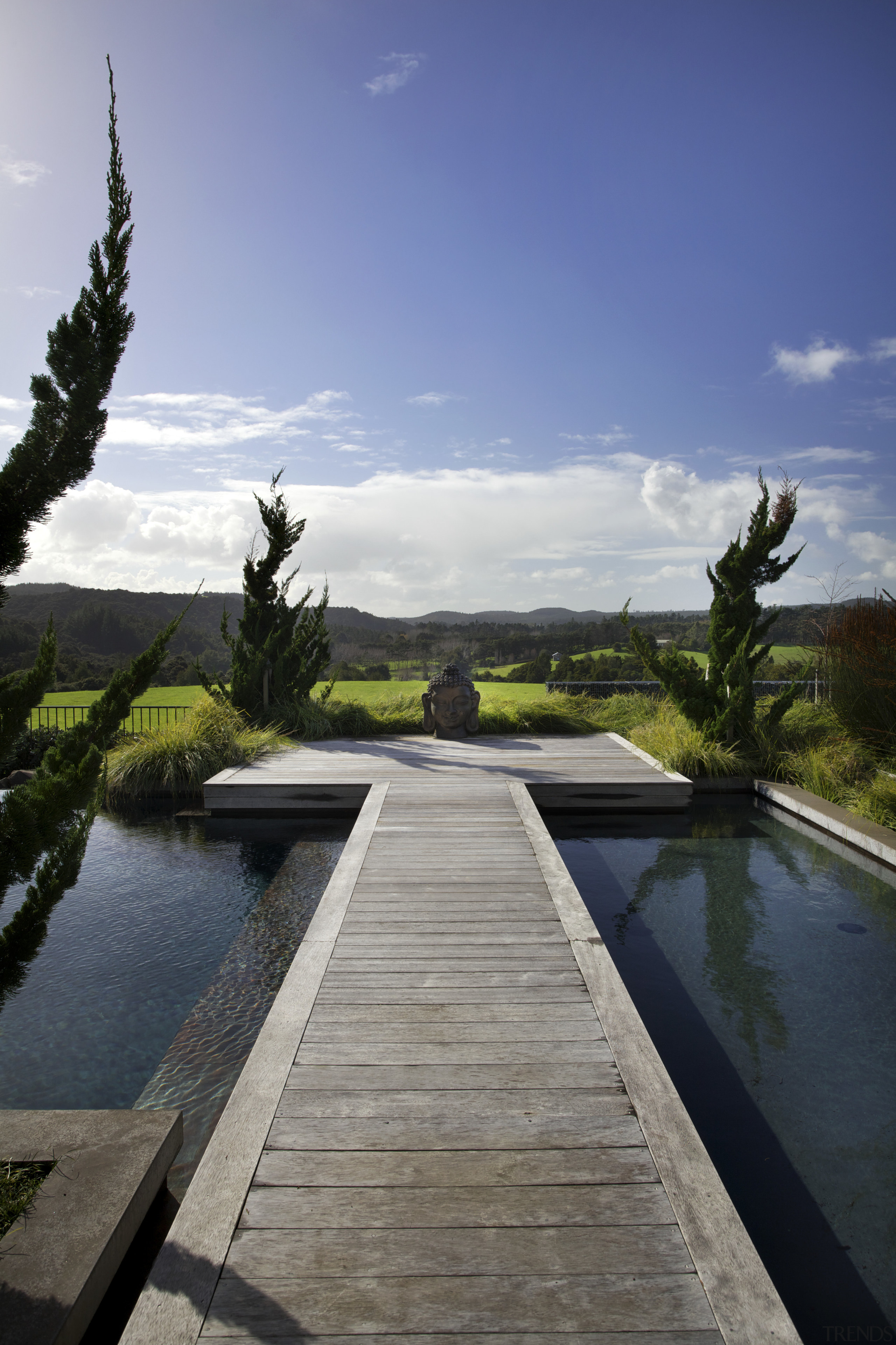 Designed by Robin Shafer, this Japanese-inspired landscape incorporates architecture, arecales, cloud, estate, landscape, palm tree, plant, reflecting pool, reflection, sky, swimming pool, tree, walkway, water, gray, blue