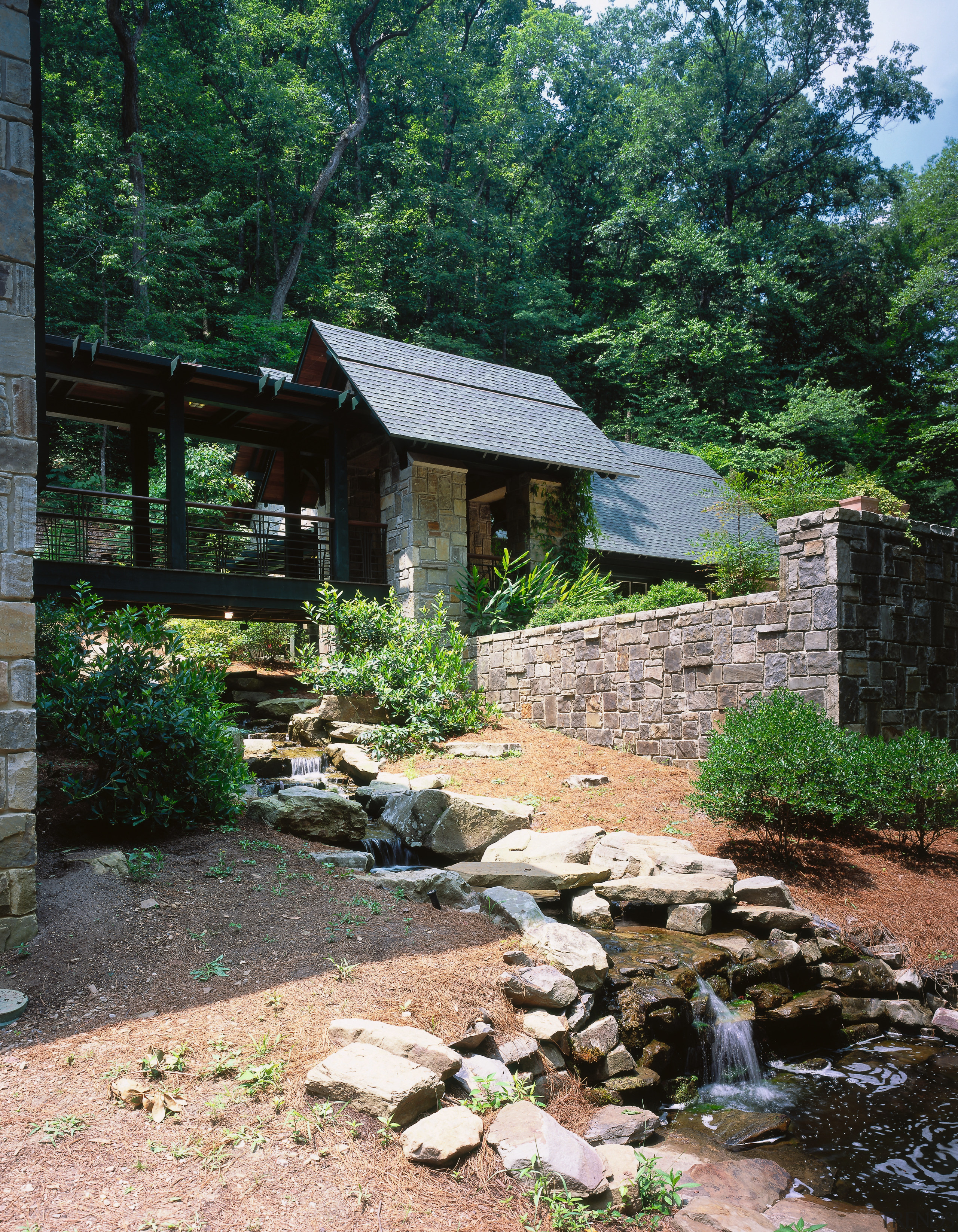 exterior view of this home nestled amogst the cottage, house, landscape, outdoor structure, plant, tree, black
