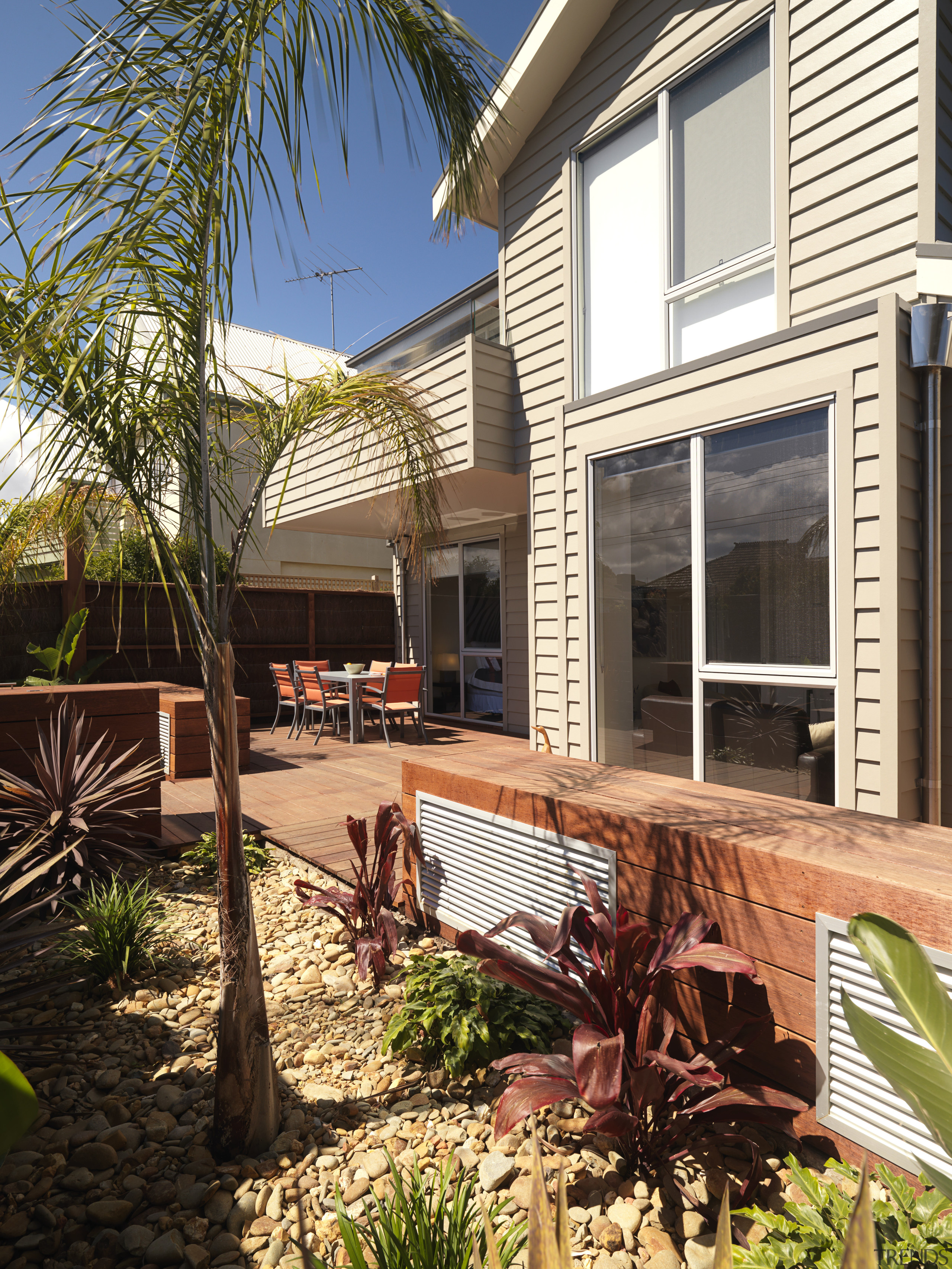 An exterior of this house featuring Merbau decking, backyard, cottage, deck, estate, facade, home, house, outdoor structure, property, real estate, residential area, siding, window, yard, brown