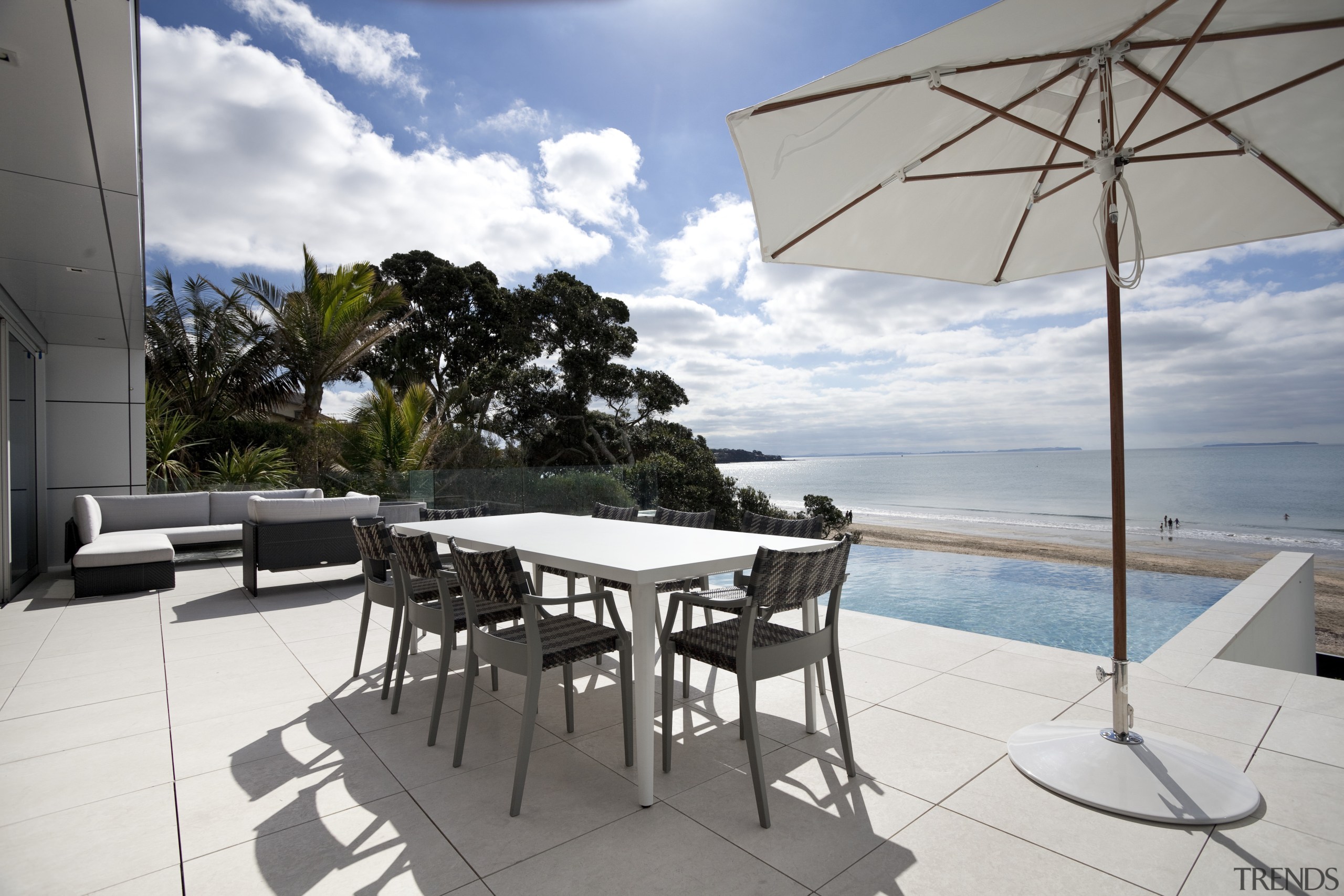 Outdoor social area with pool and beach. - apartment, condominium, estate, house, outdoor furniture, penthouse apartment, property, real estate, resort, table, vacation, villa, white, gray