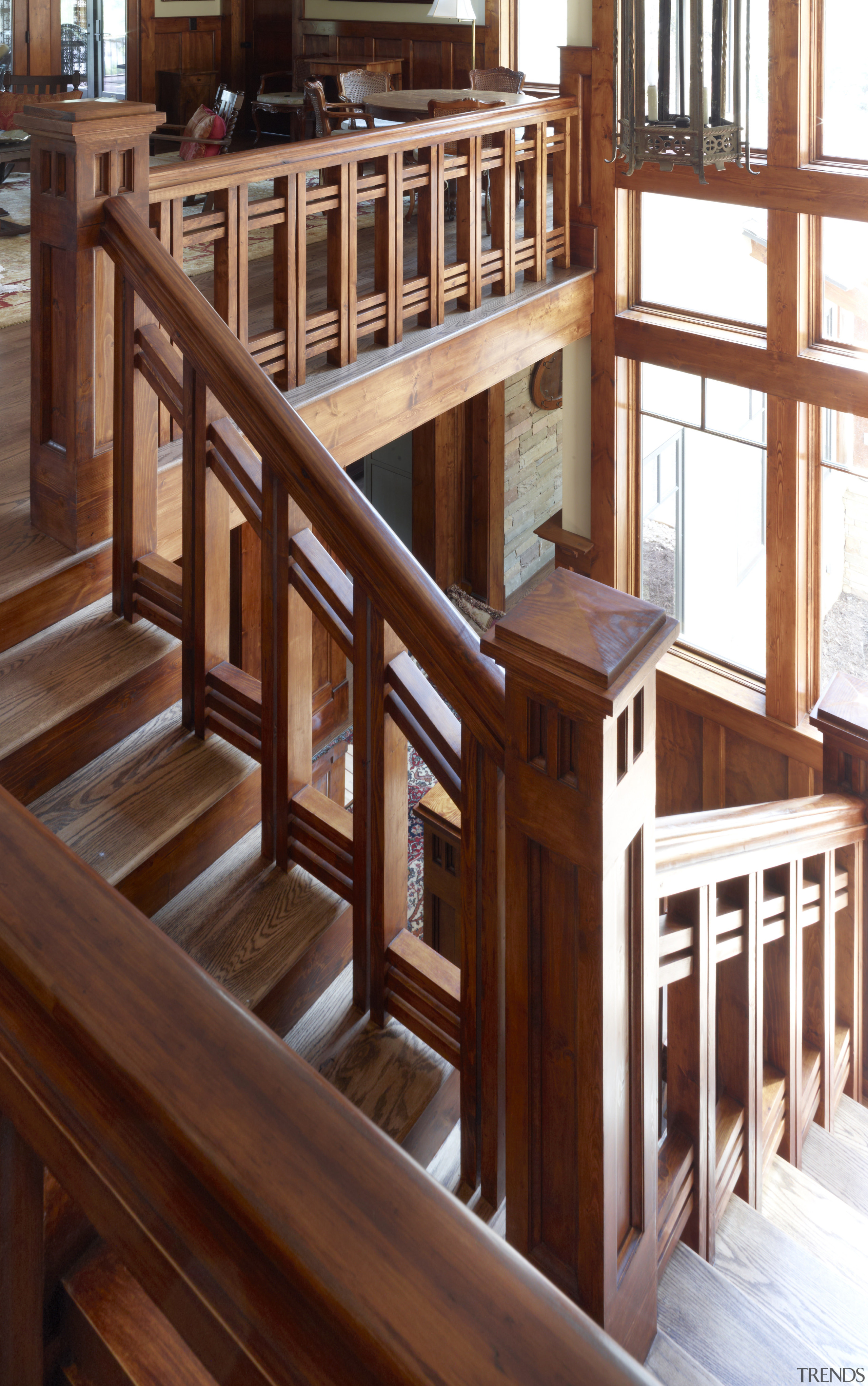 Wood stairs in this remodeled house reference the baluster, floor, flooring, furniture, handrail, hardwood, stairs, wood, wood stain, red, brown