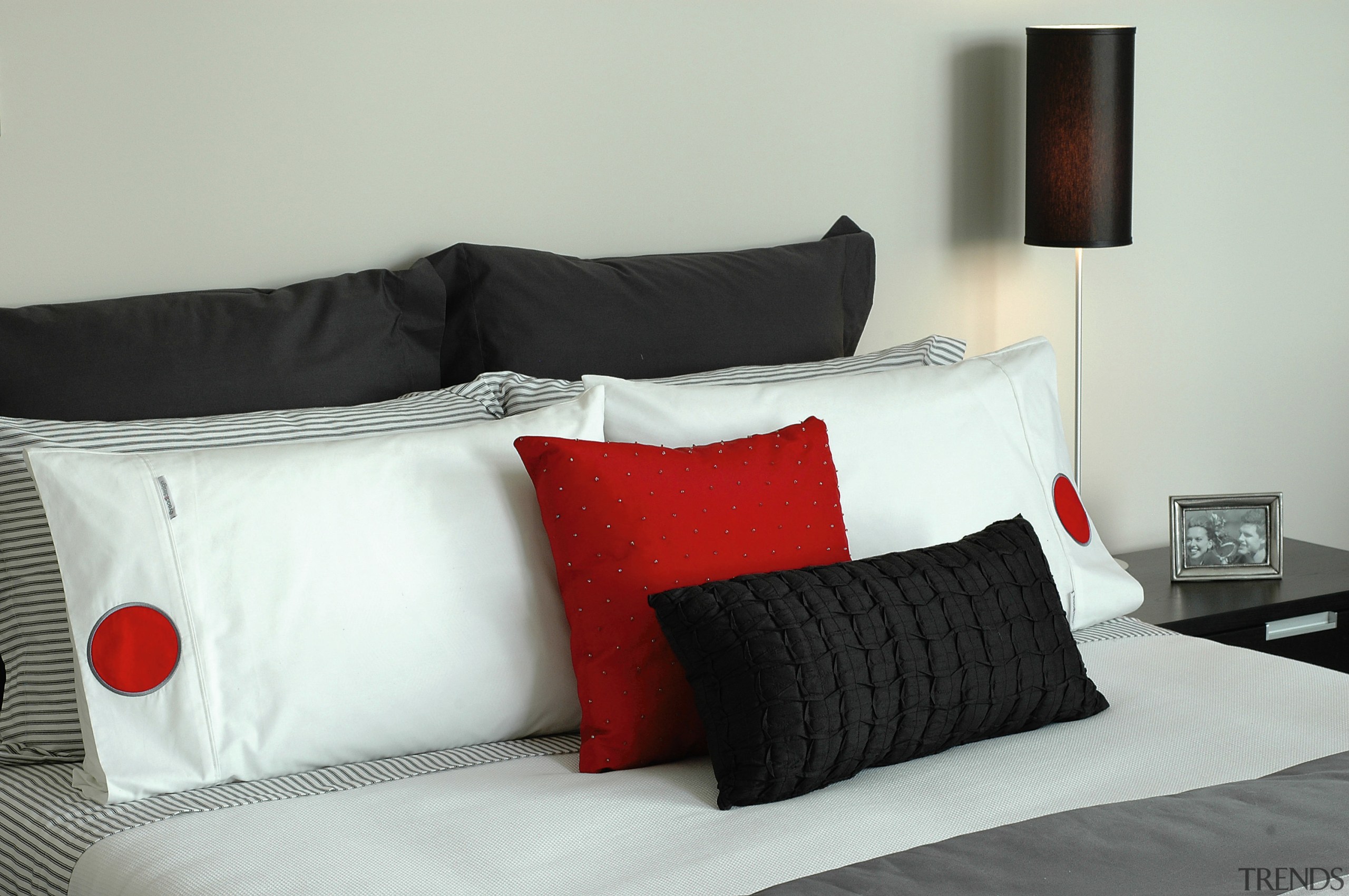 Bedroom setting with black, white and red bedding. bed, bed frame, bed sheet, bedding, bedroom, comfort, couch, cushion, duvet cover, furniture, home, interior design, linens, mattress, pillow, product design, room, suite, textile, white, gray