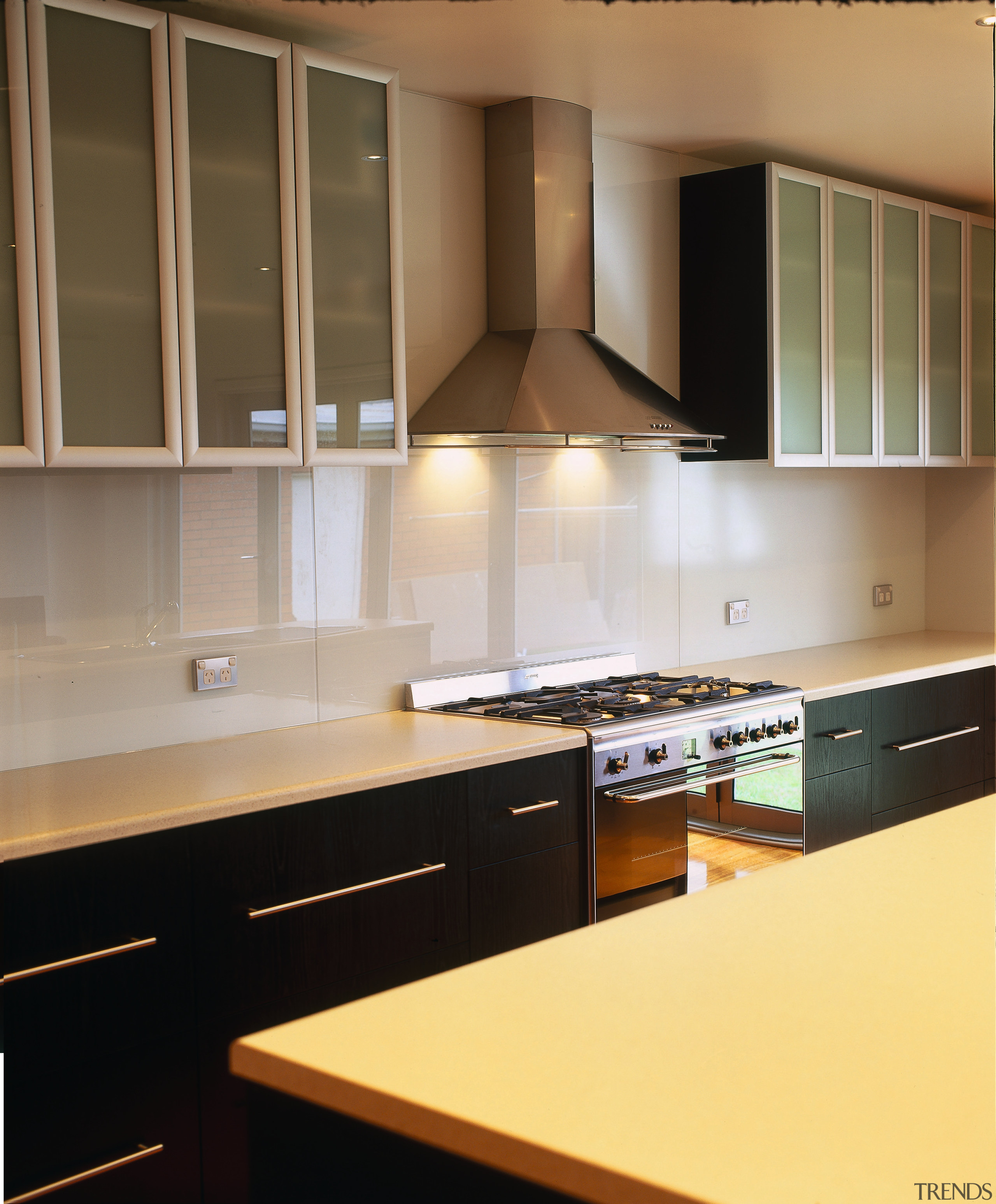 Kitchen with black cabinetry, cream benchtop, glass and cabinetry, countertop, cuisine classique, interior design, kitchen, room, under cabinet lighting, brown