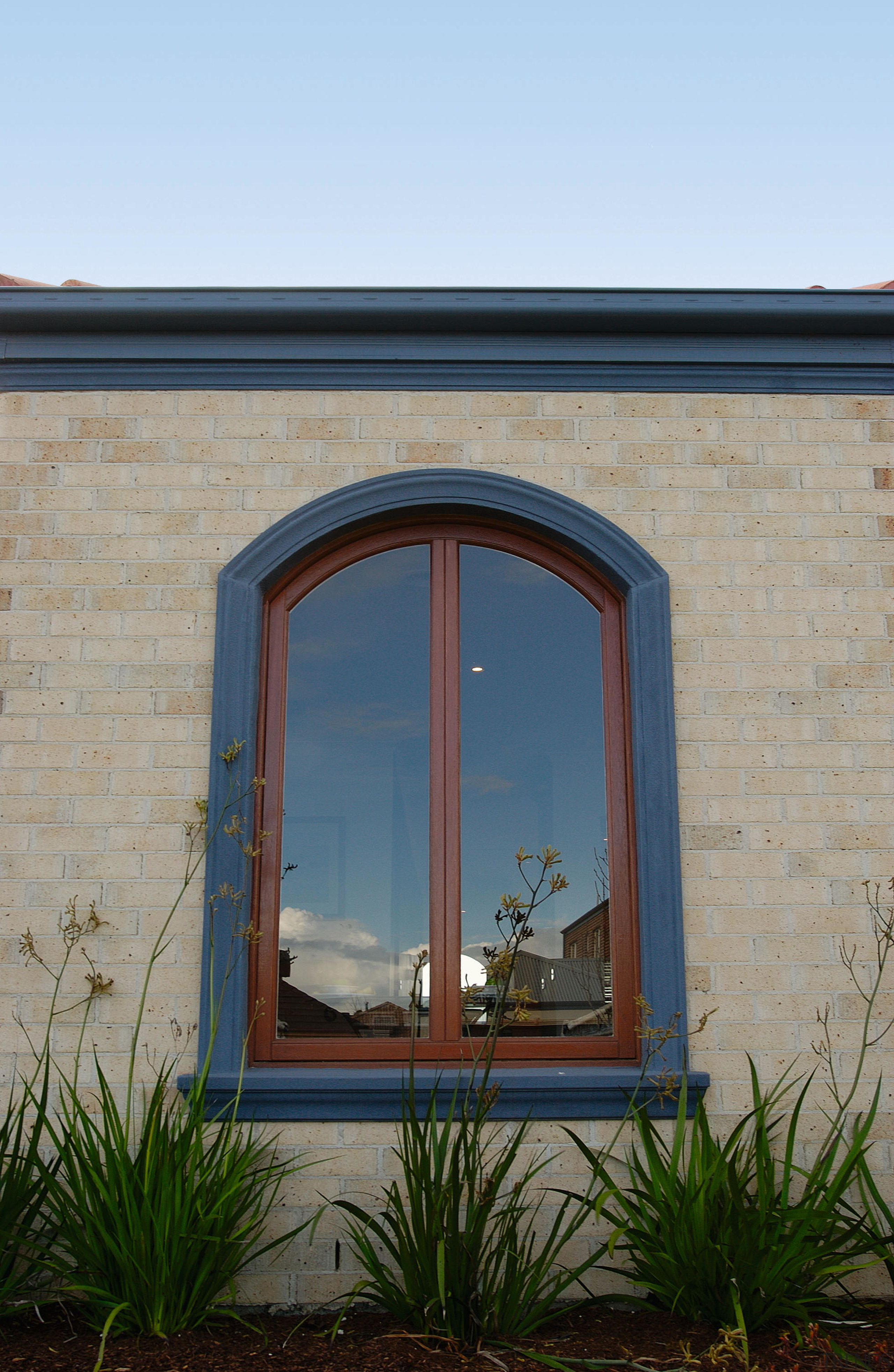 Exterior of brick clad house featuring timber arched arch, architecture, facade, home, sky, wall, window, teal, gray
