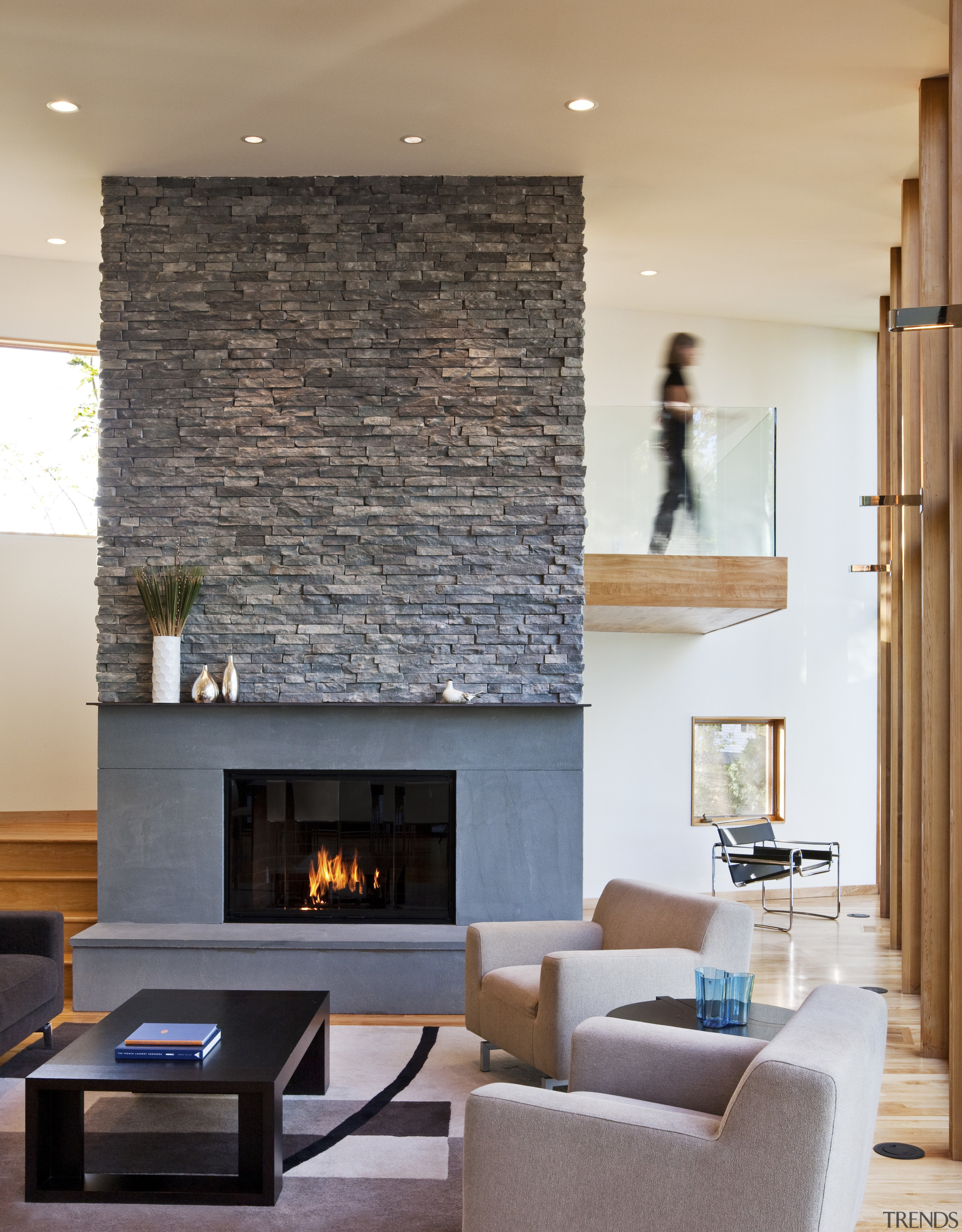 View of living area featuring a bluestone fire ceiling, fireplace, floor, flooring, hardwood, hearth, home, interior design, living room, lobby, room, table, wall, wood flooring, gray