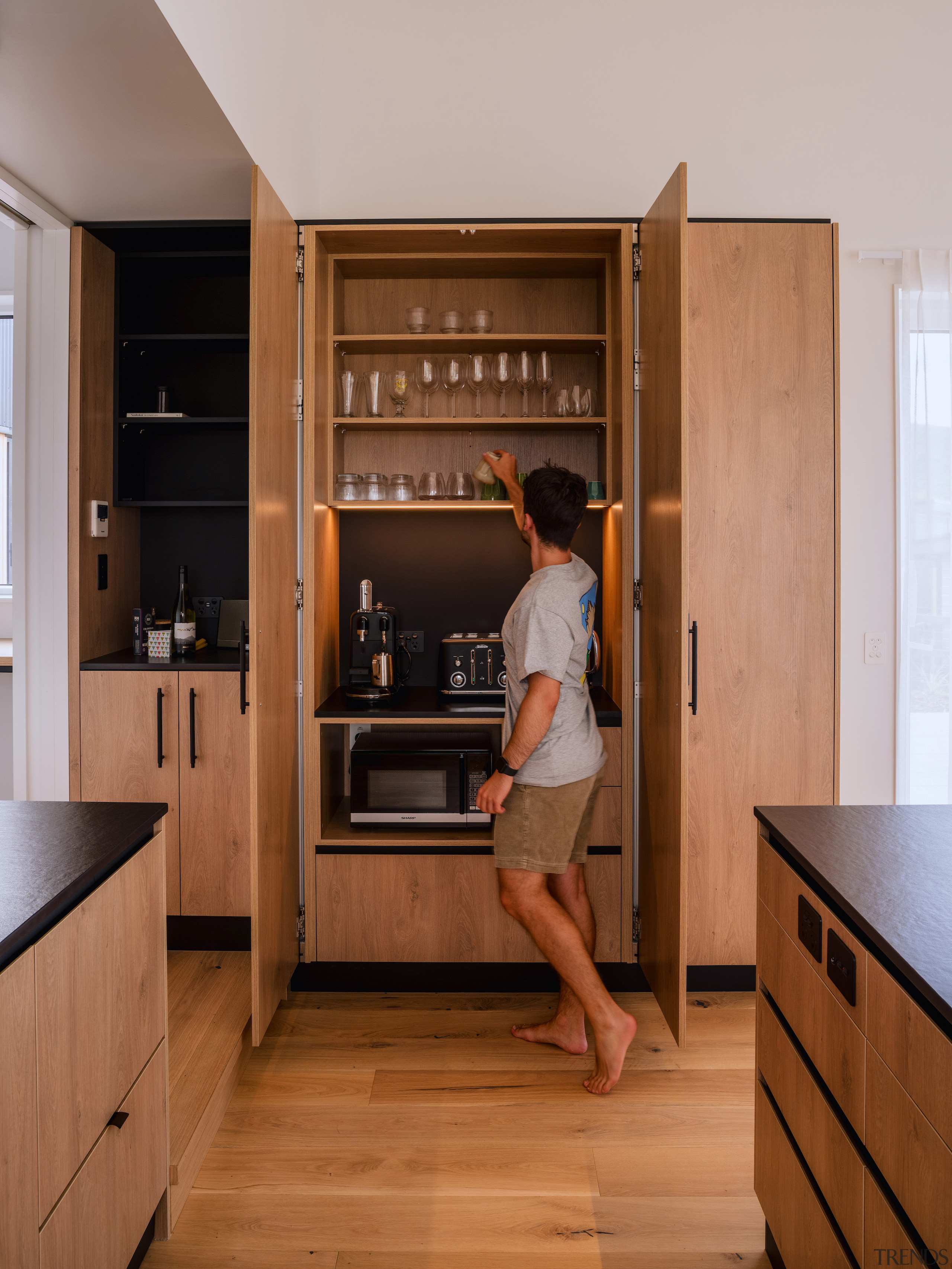 The kitchen's warm wood cabinetry encloses a drinks 