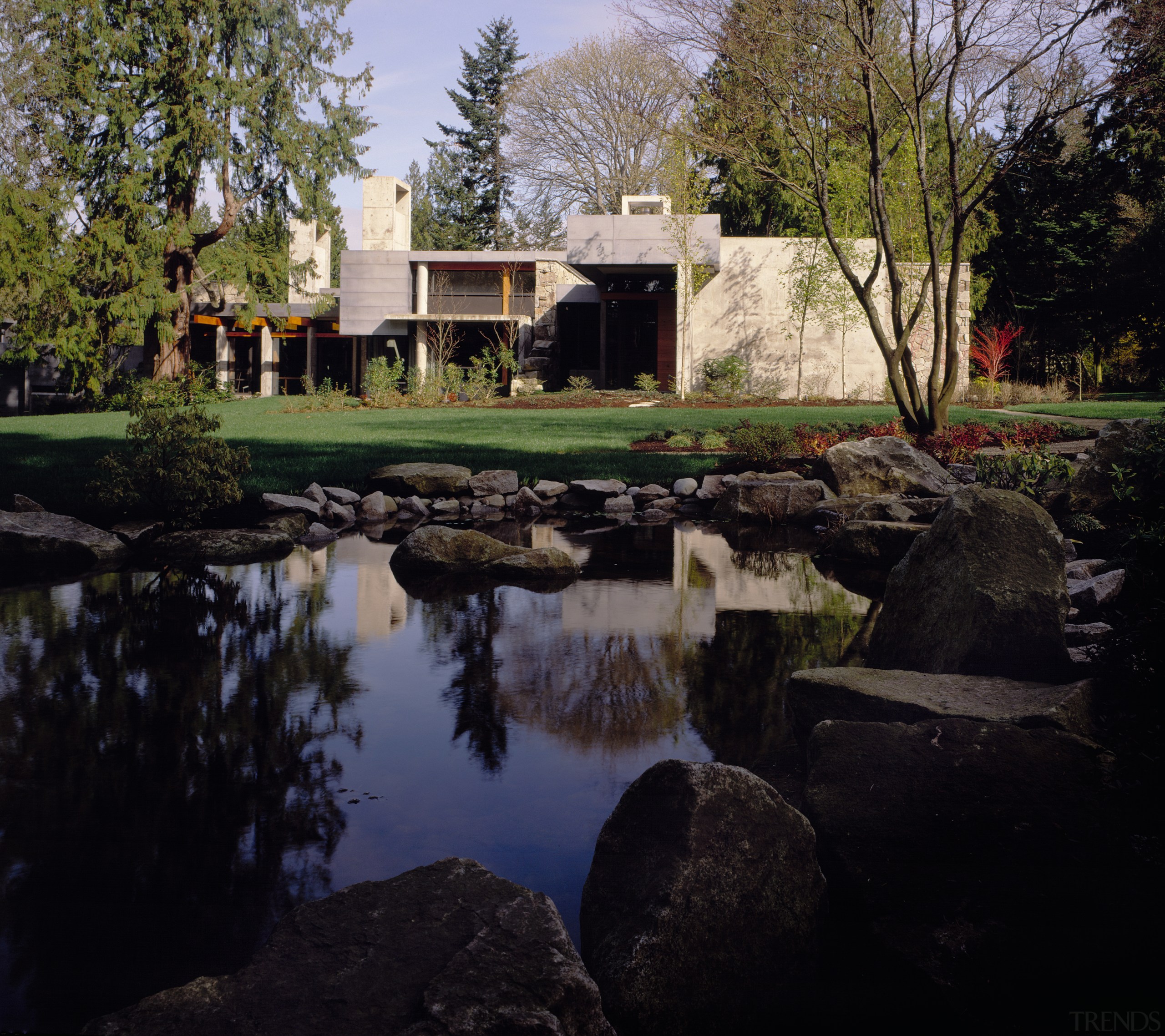 view of this home looking out over the architecture, estate, grass, home, house, landscape, plant, pond, reflection, sky, tree, water, black