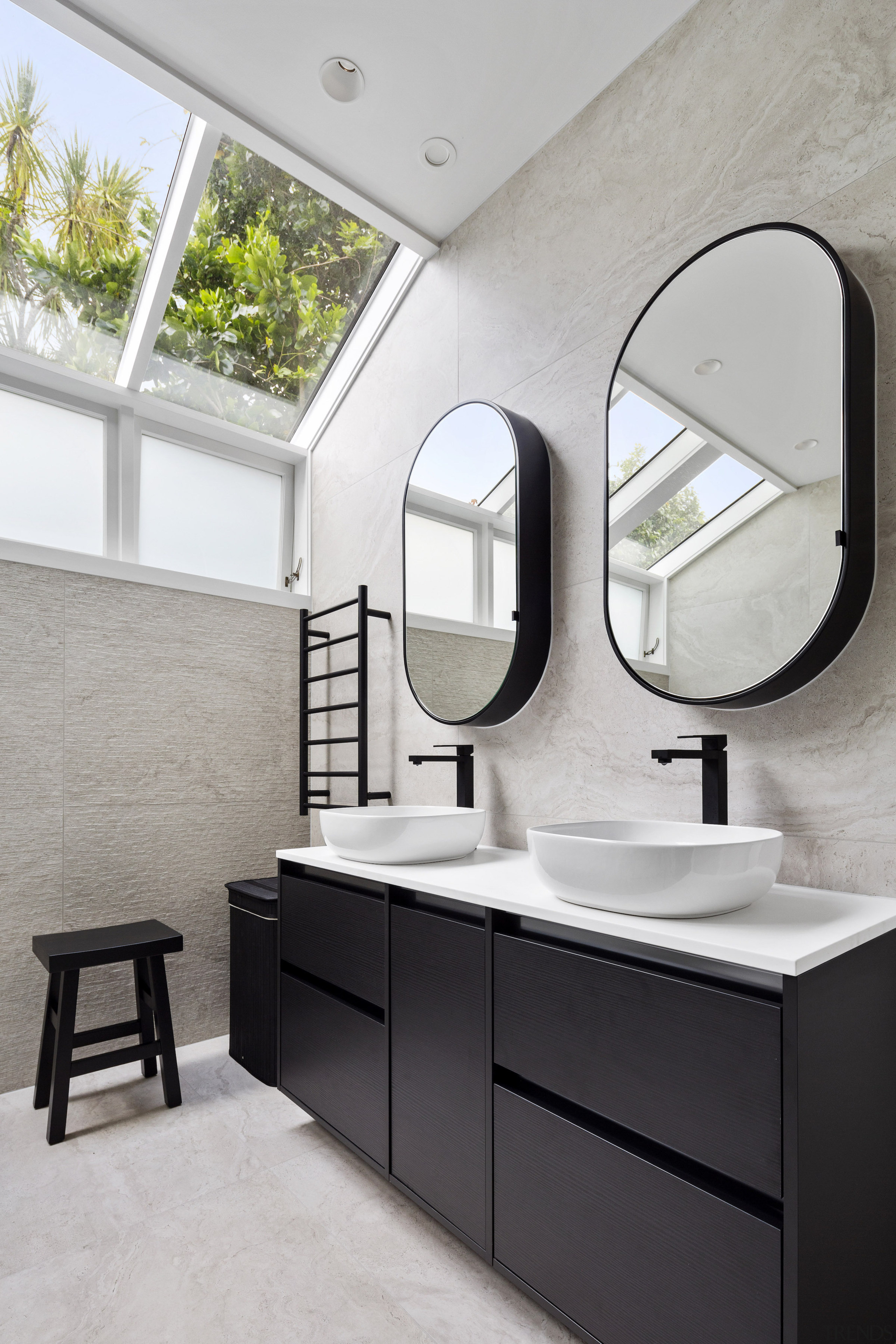 The oval vanity mirrors reflect light and greenery 