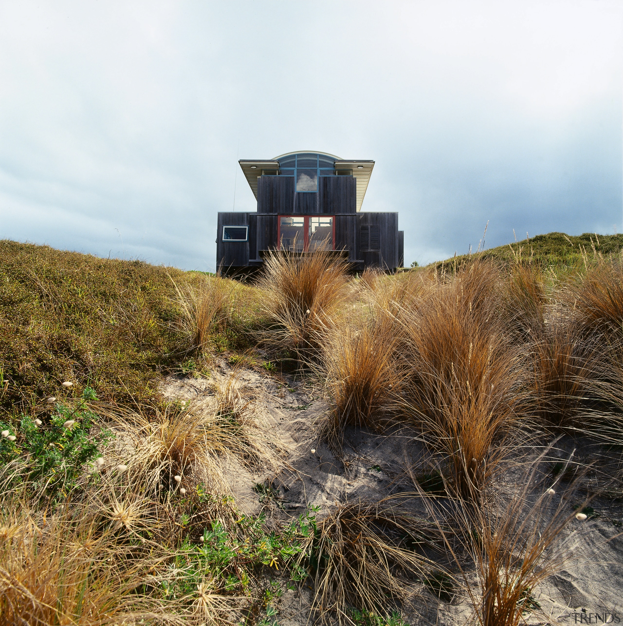 An exterior view of this coastal property on ecoregion, grass, grass family, grassland, plant, plant community, prairie, shrubland, sky, soil, white, brown