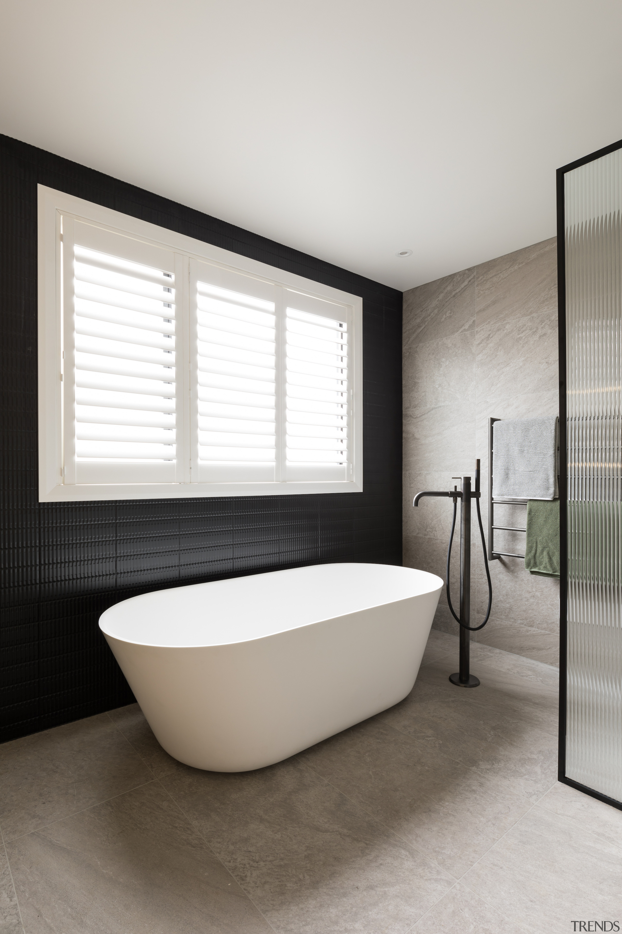 The bath stands out against the dark tilework. 