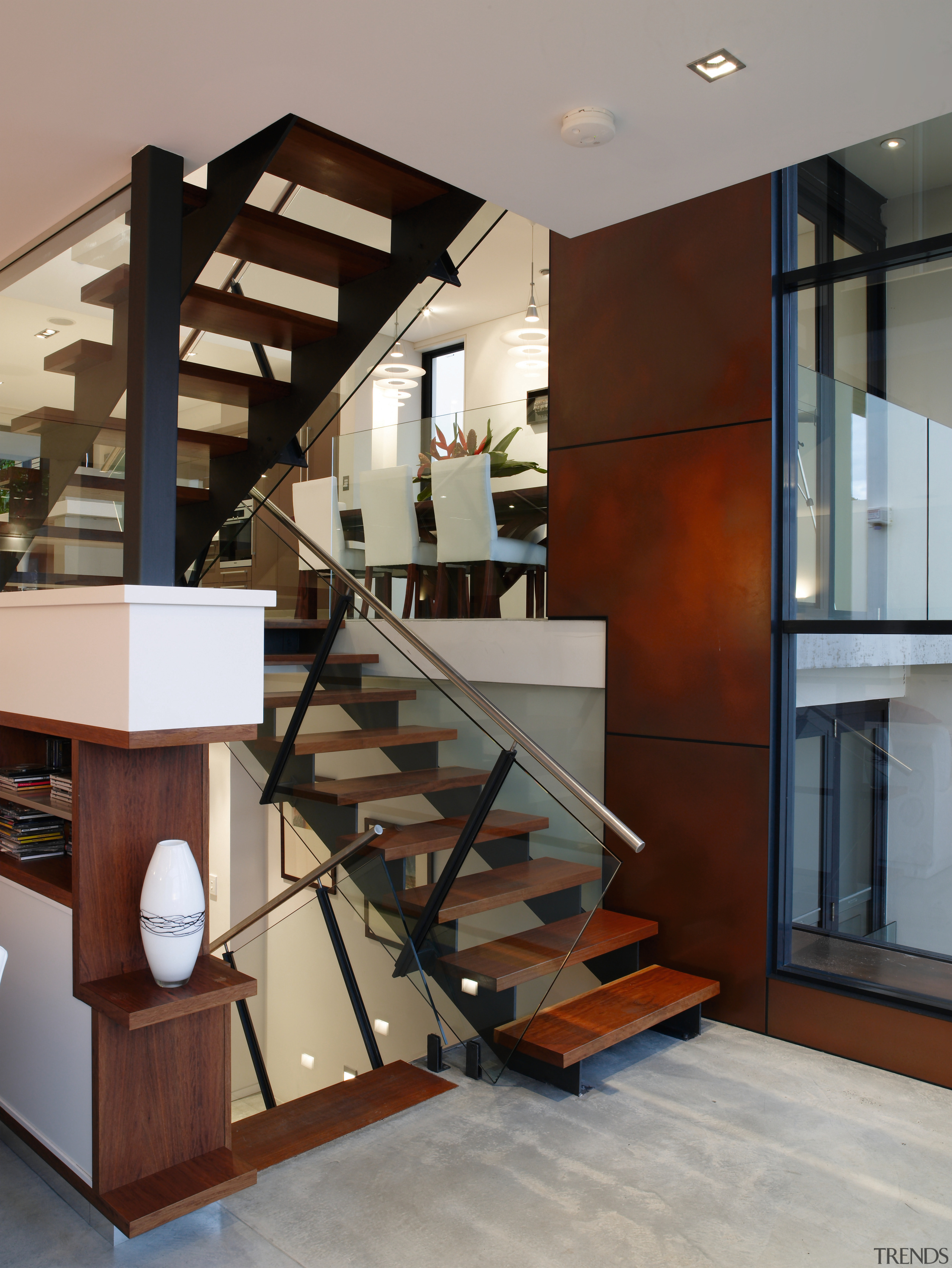 A view of the staircase featuring stainless steel floor, flooring, handrail, interior design, stairs, structure, gray, brown