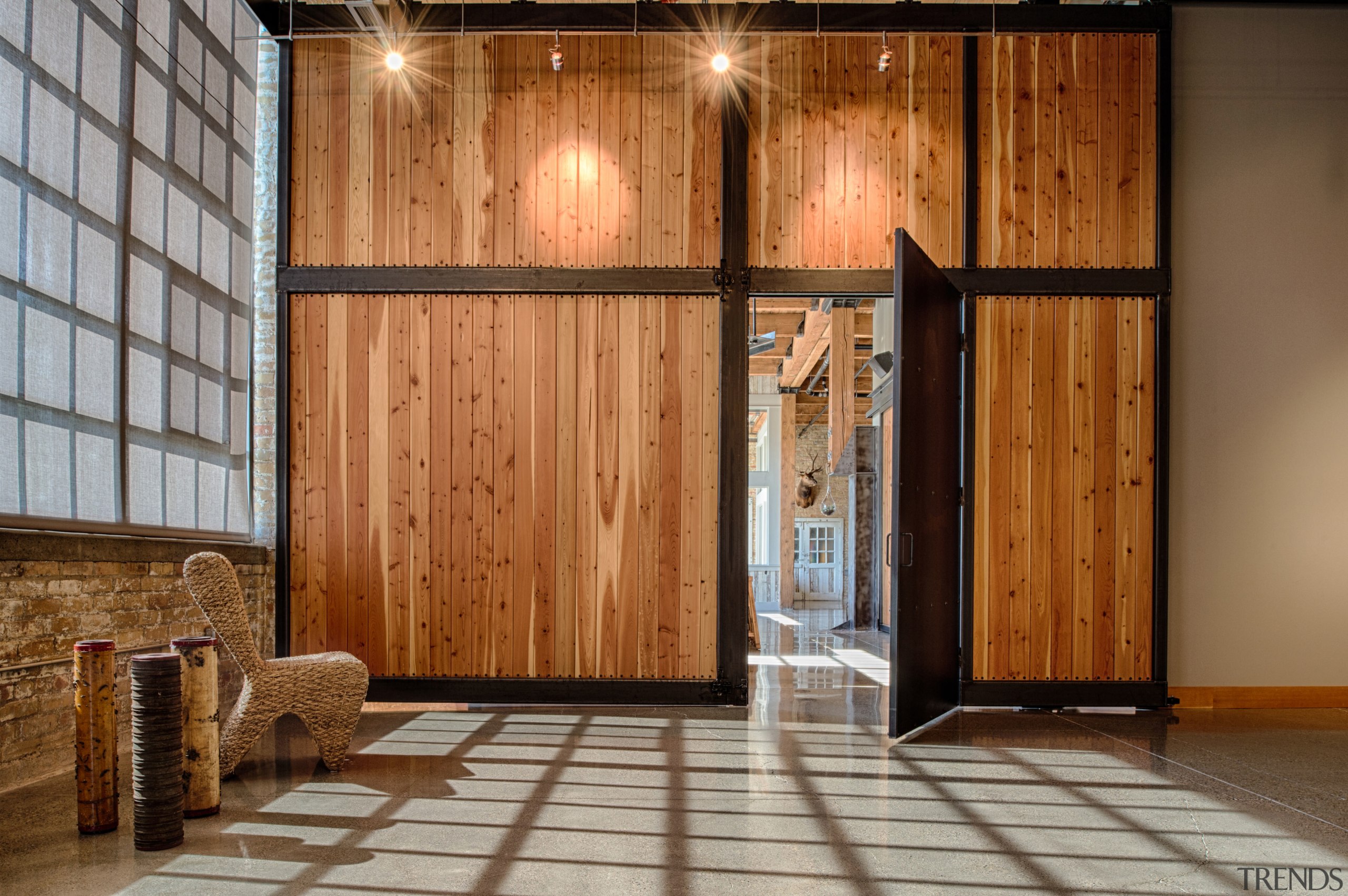 In this converted heritage building a large sliding door, floor, flooring, lobby, wood, wood stain, brown