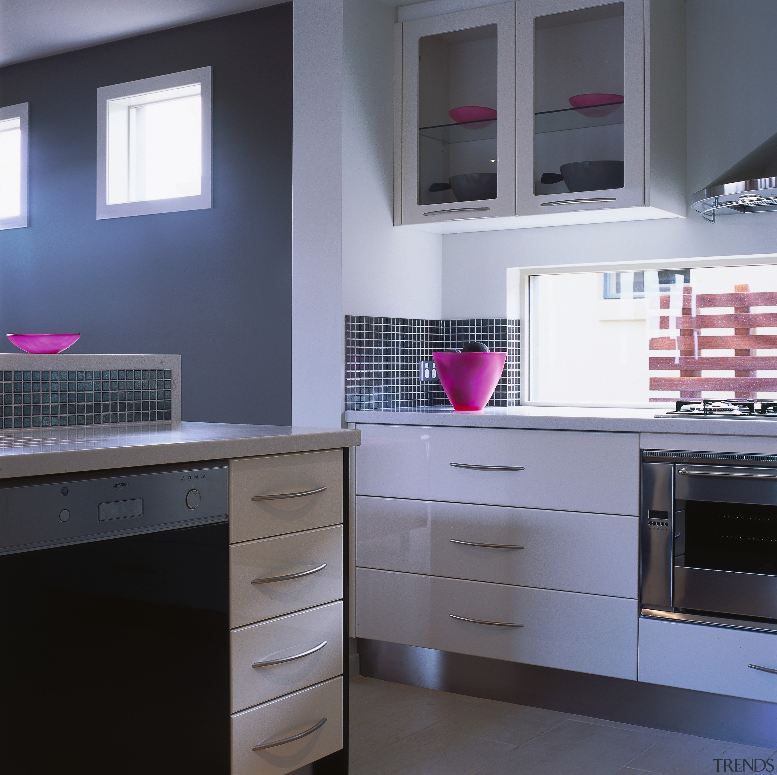 Kitchen with white cabinetry, stainless steel oven, glass cabinetry, chest of drawers, countertop, furniture, interior design, kitchen, room, gray, black