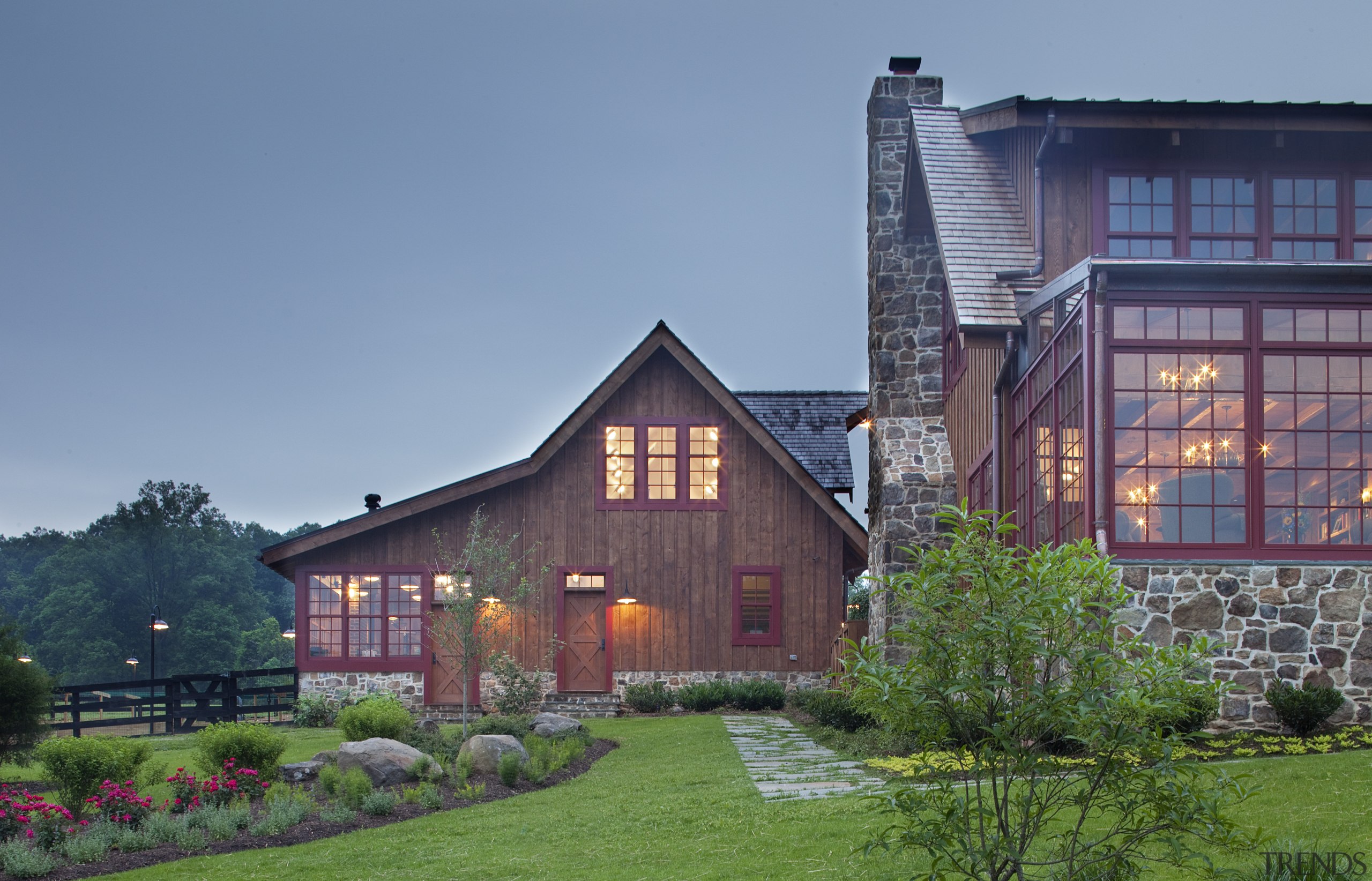 View of wooden buildings with red window frames. architecture, building, cottage, estate, evening, facade, farmhouse, grass, home, house, landscape, property, real estate, residential area, roof, sky, suburb, teal