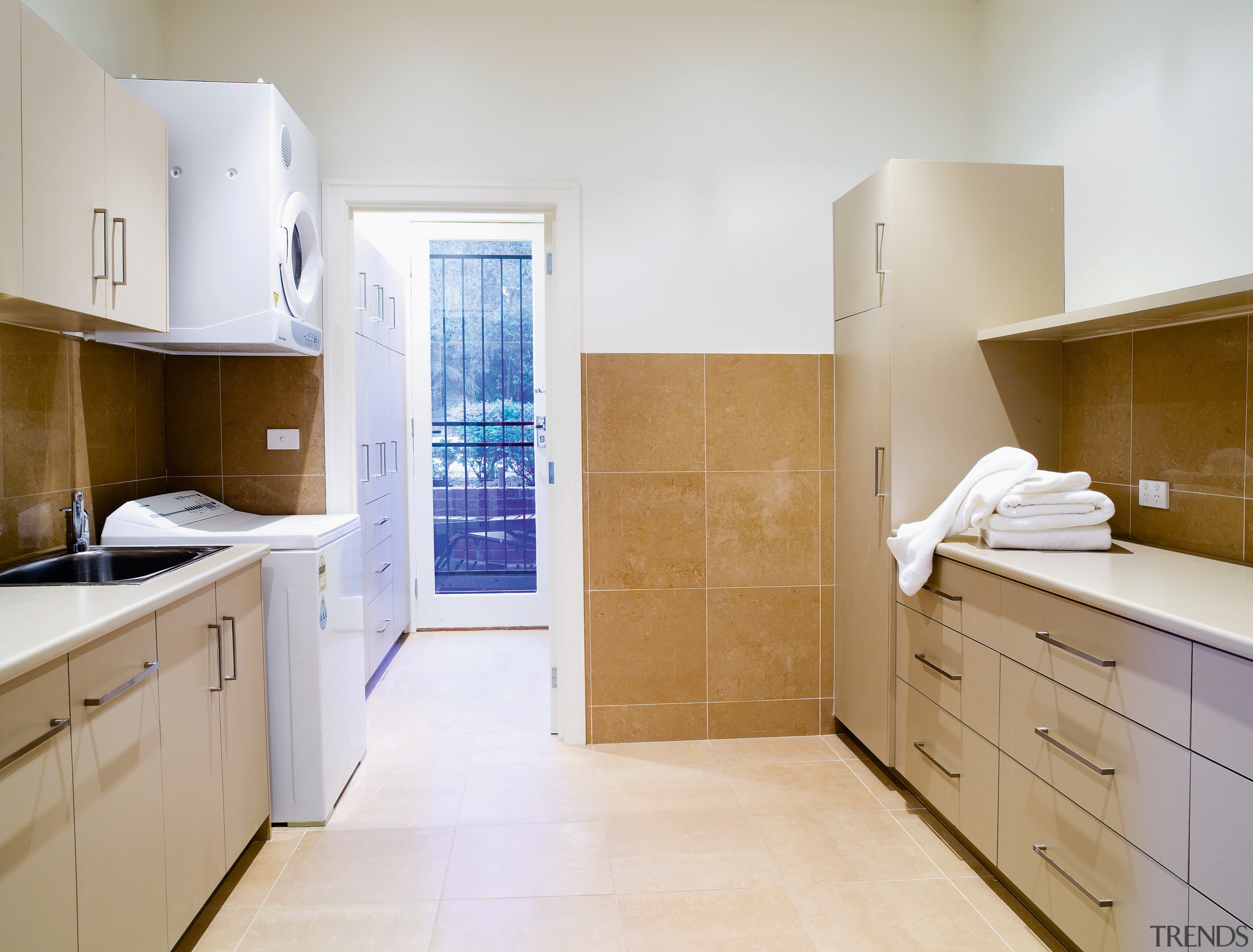 View of a large laundry which features cabinetry, bathroom, cabinetry, countertop, cuisine classique, floor, flooring, home, home appliance, interior design, kitchen, property, real estate, room, sink, tile, gray