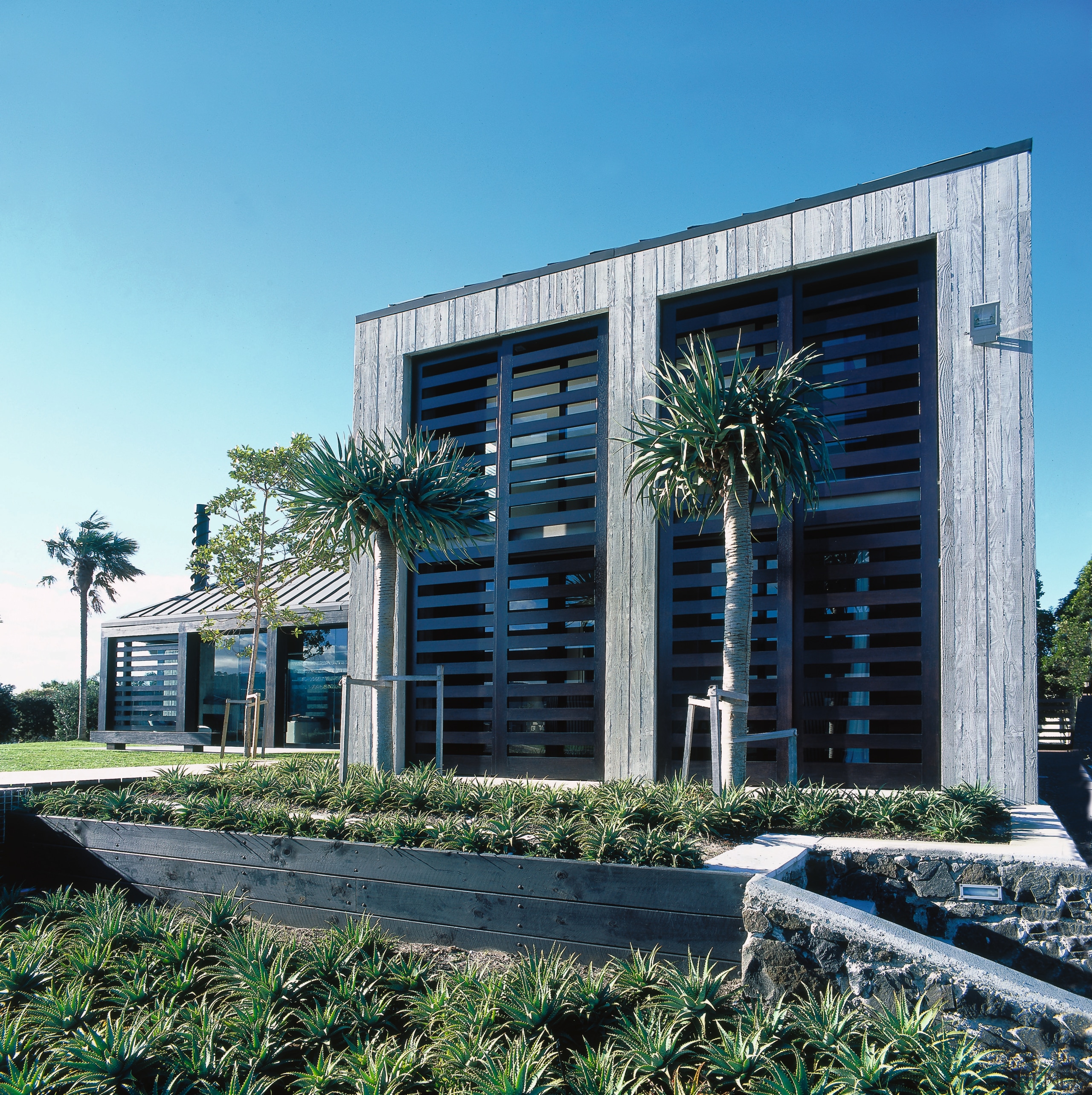 view of the landscaped carden and house featuring architecture, building, commercial building, condominium, corporate headquarters, facade, headquarters, home, house, mixed use, real estate, teal